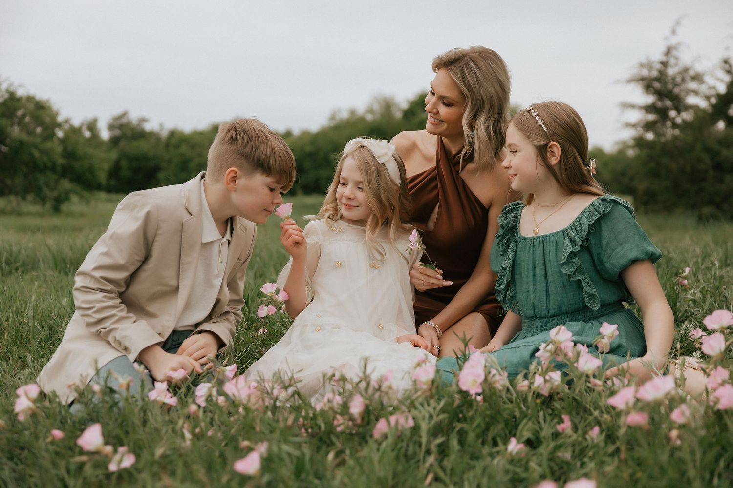 Family sitting together in a blooming flower field during golden hour.