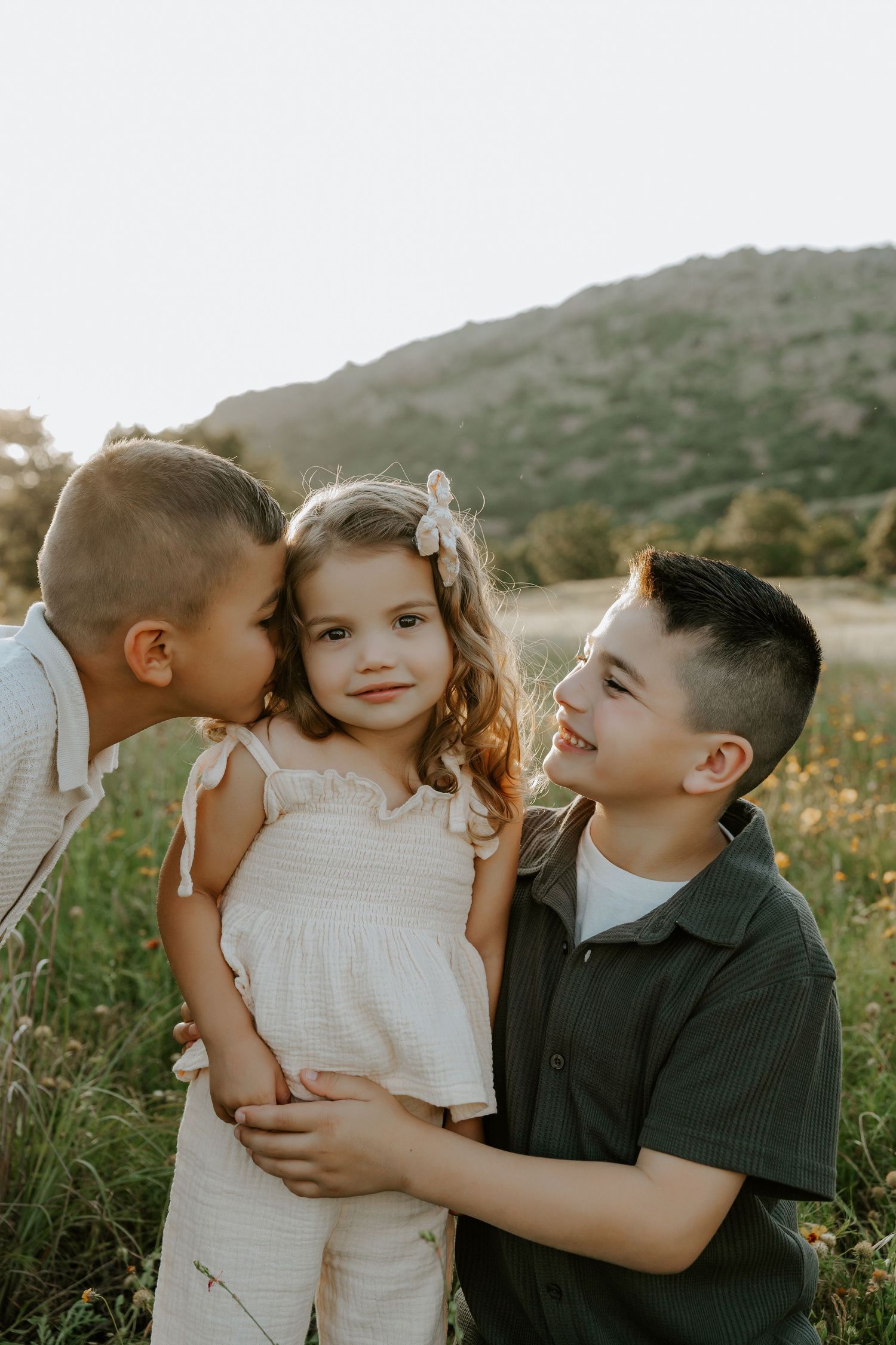 Sweet candid moments between children in a sunlit field.