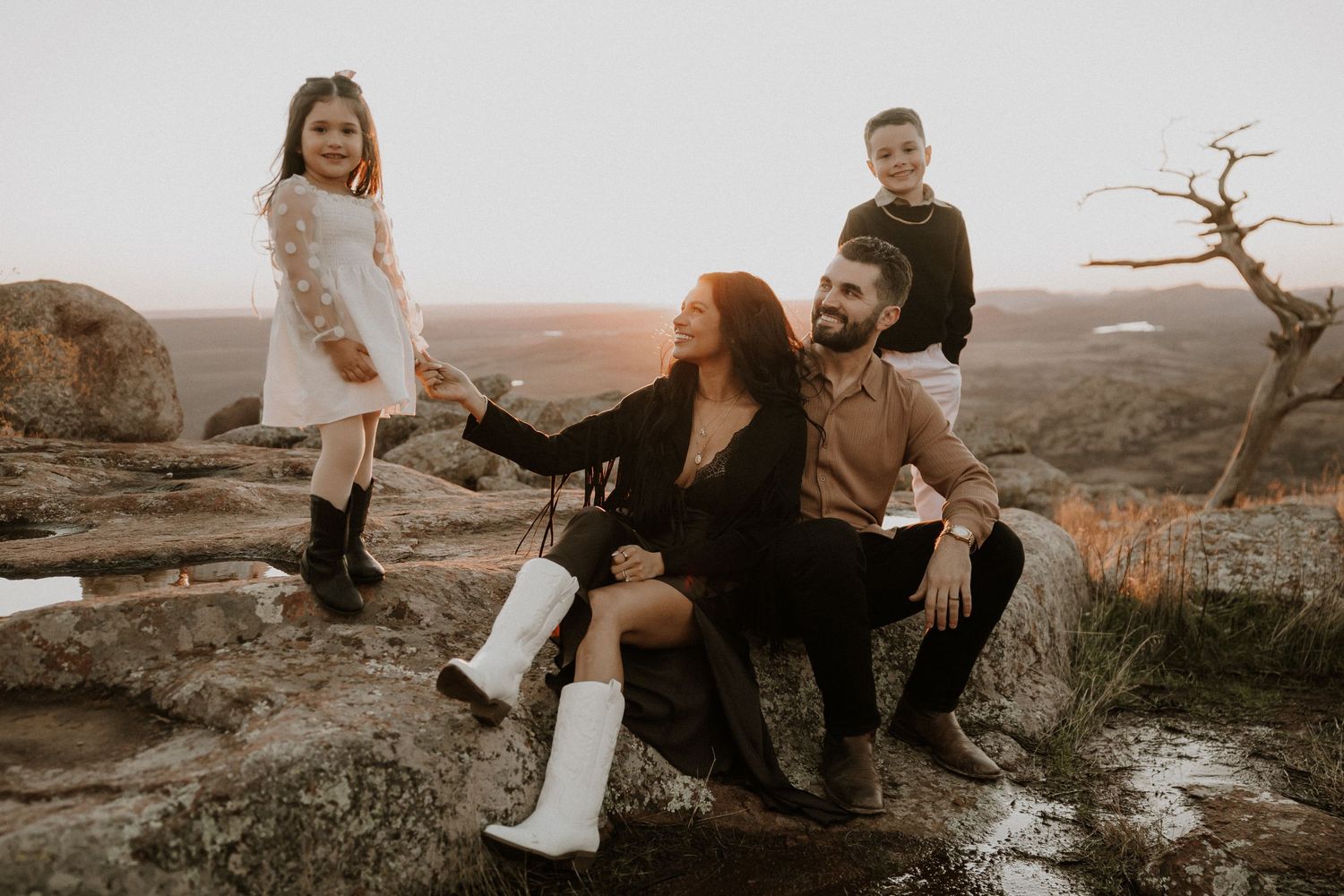 Family enjoys playful moments together outdoors during sunset photography session.