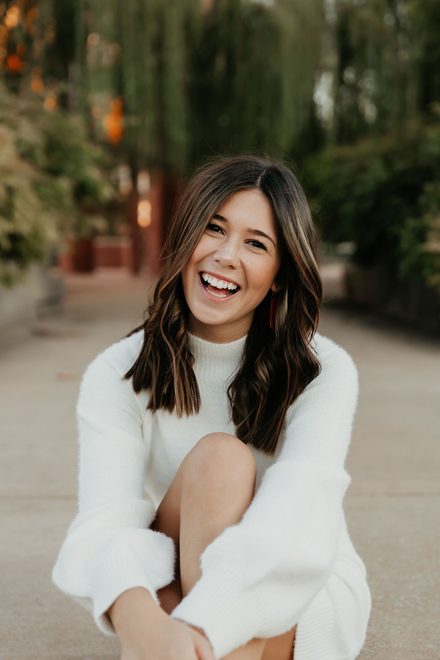 Portrait session in white sweater against autumn outdoor background.