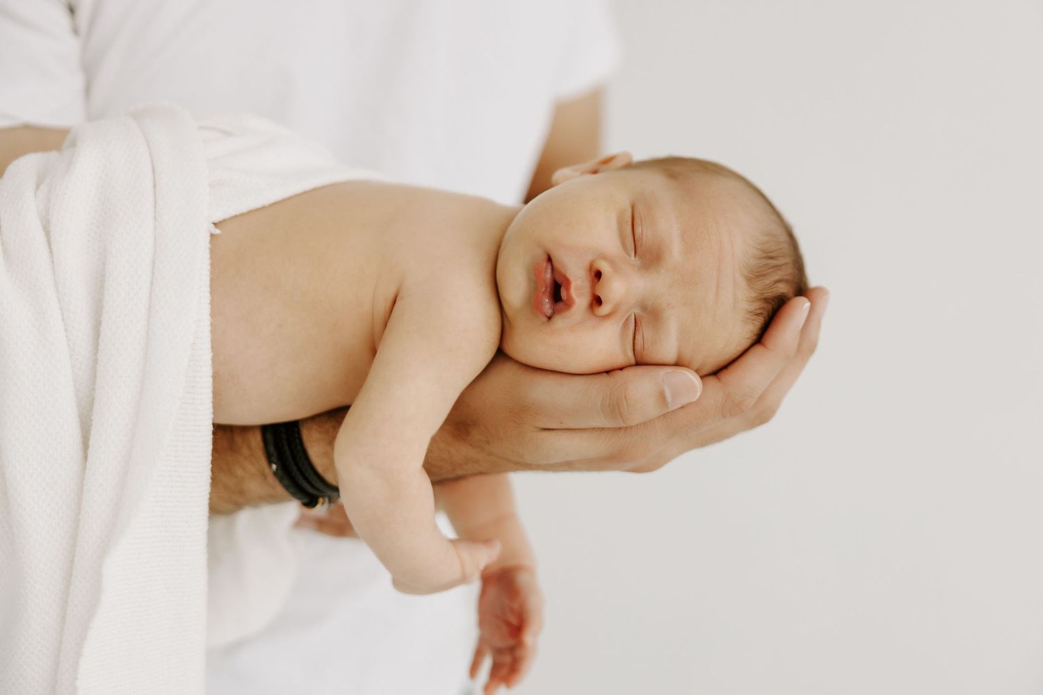 Tender newborn photography session with gentle holding poses.