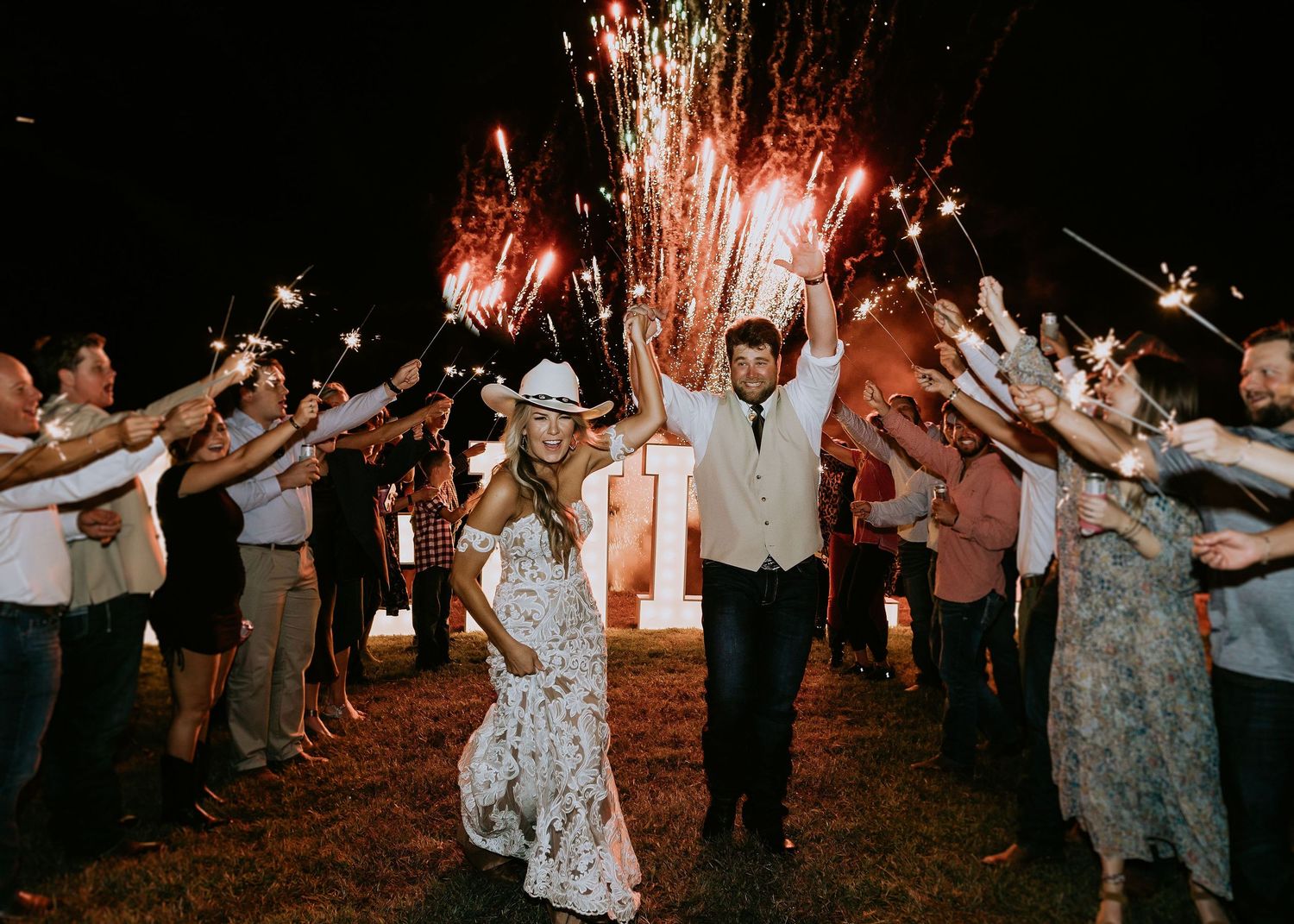 Wedding guests celebrate with sparklers creating a magical nighttime send-off for the newlyweds.