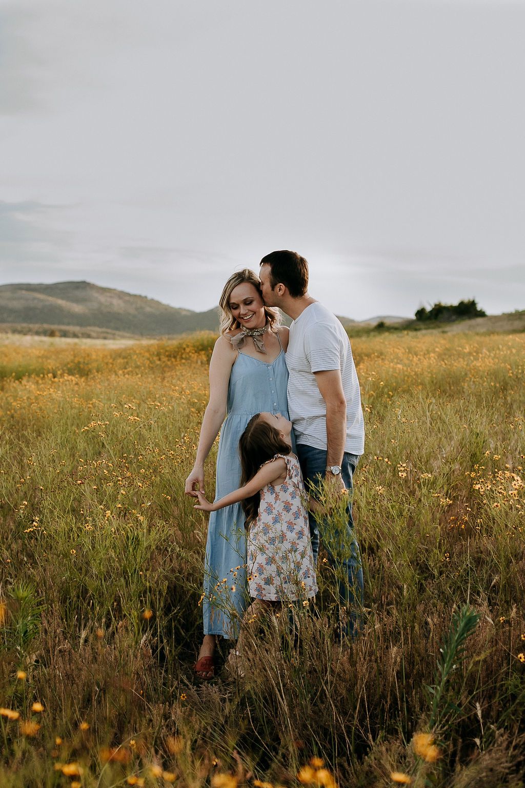 Family sharing tender moment together in wildflower meadow at sunset.