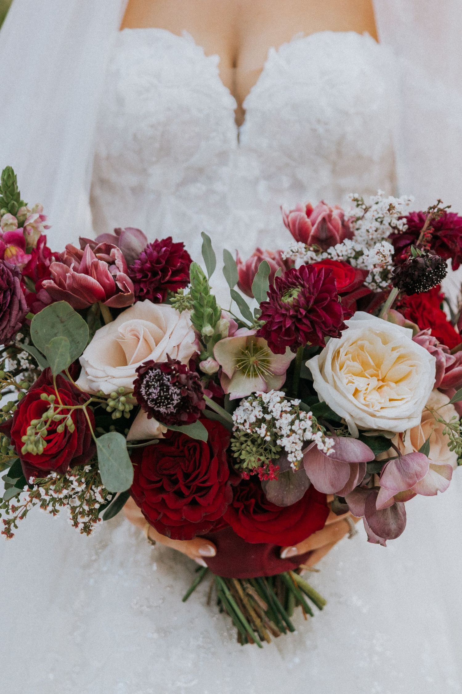 Stunning wedding bouquet featuring burgundy and blush flowers with delicate greenery and roses.