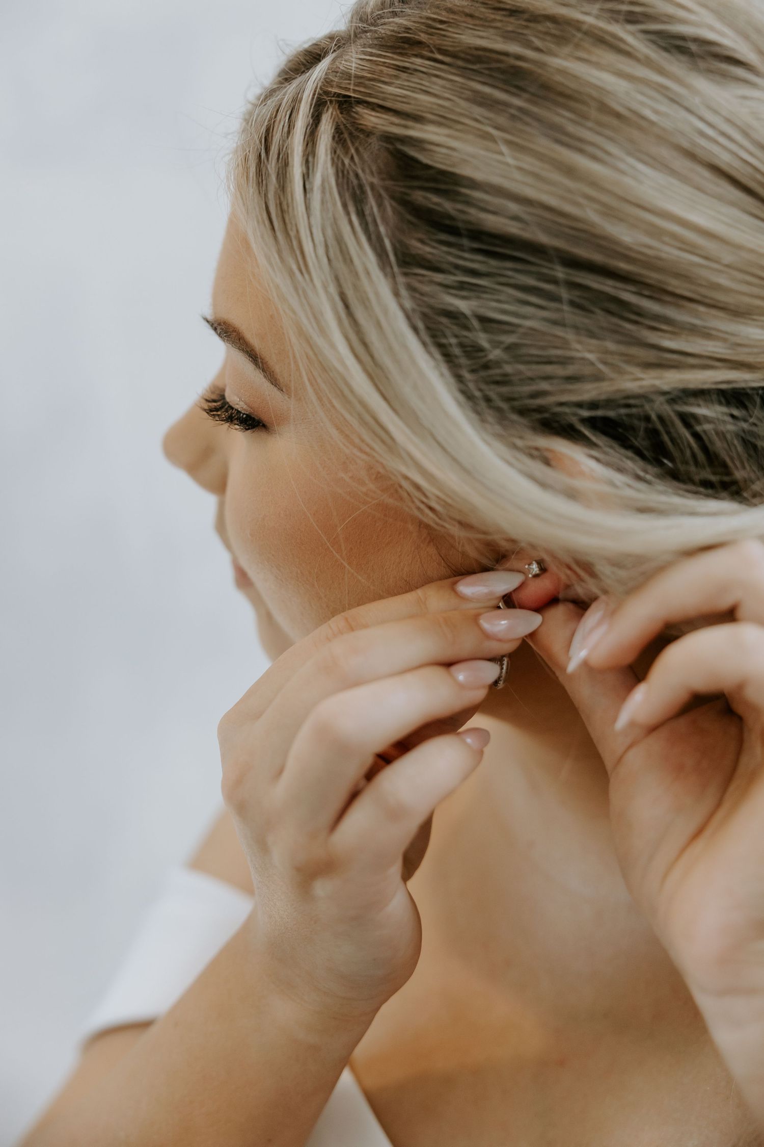 Close-up shots of someone putting on delicate earrings before a wedding ceremony.
