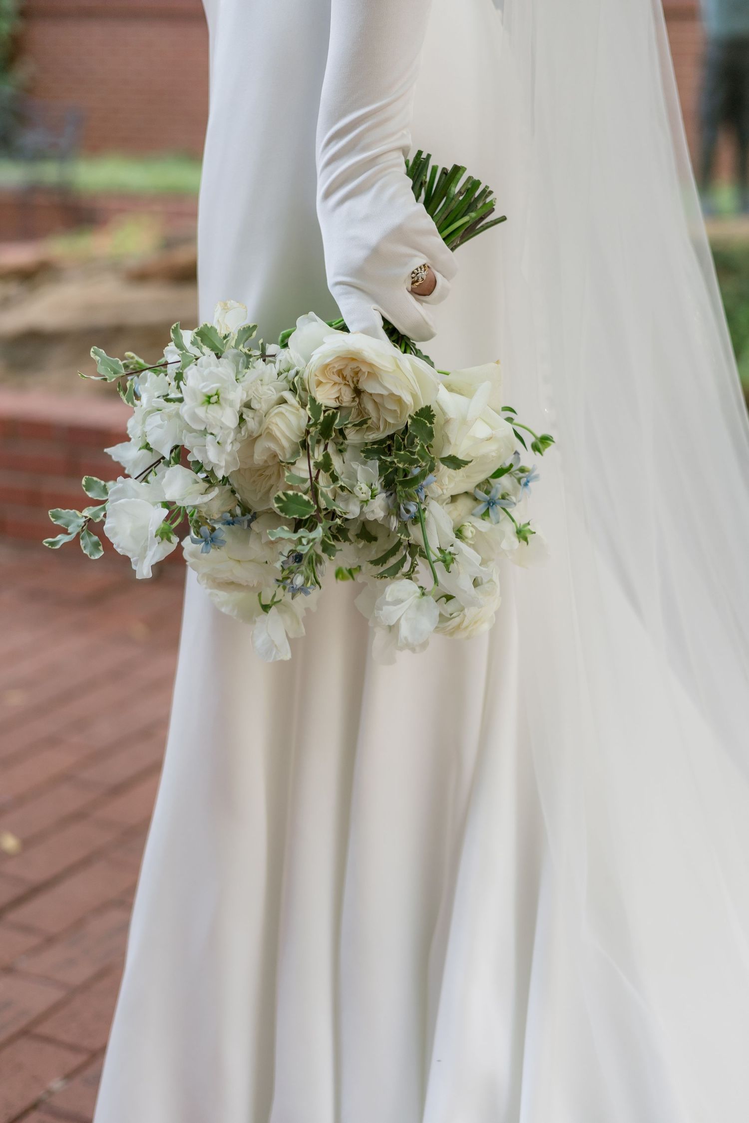 Close-up details of delicate white floral bouquet arrangements against a flowing white wedding dress.