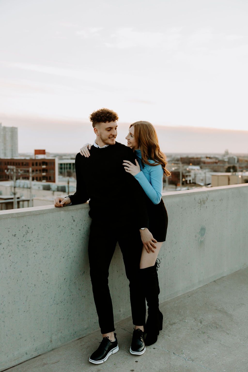 Couple embracing on urban rooftop with city backdrop.