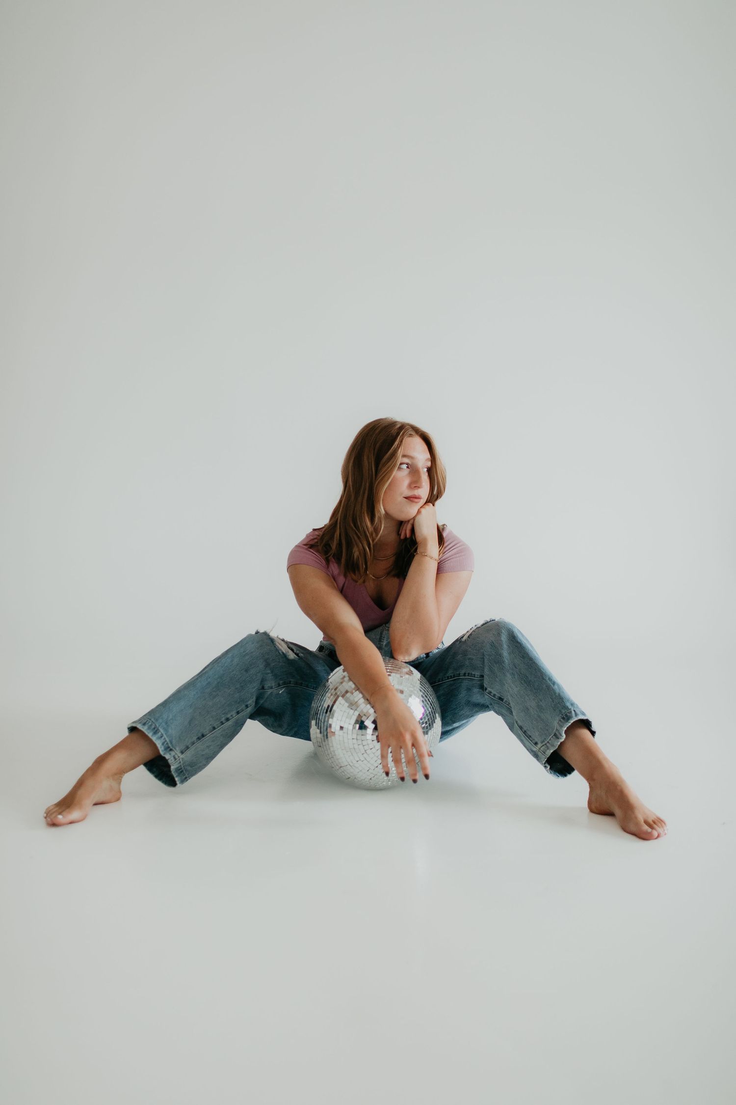 Casual poses on white floor wearing distressed denim jeans.