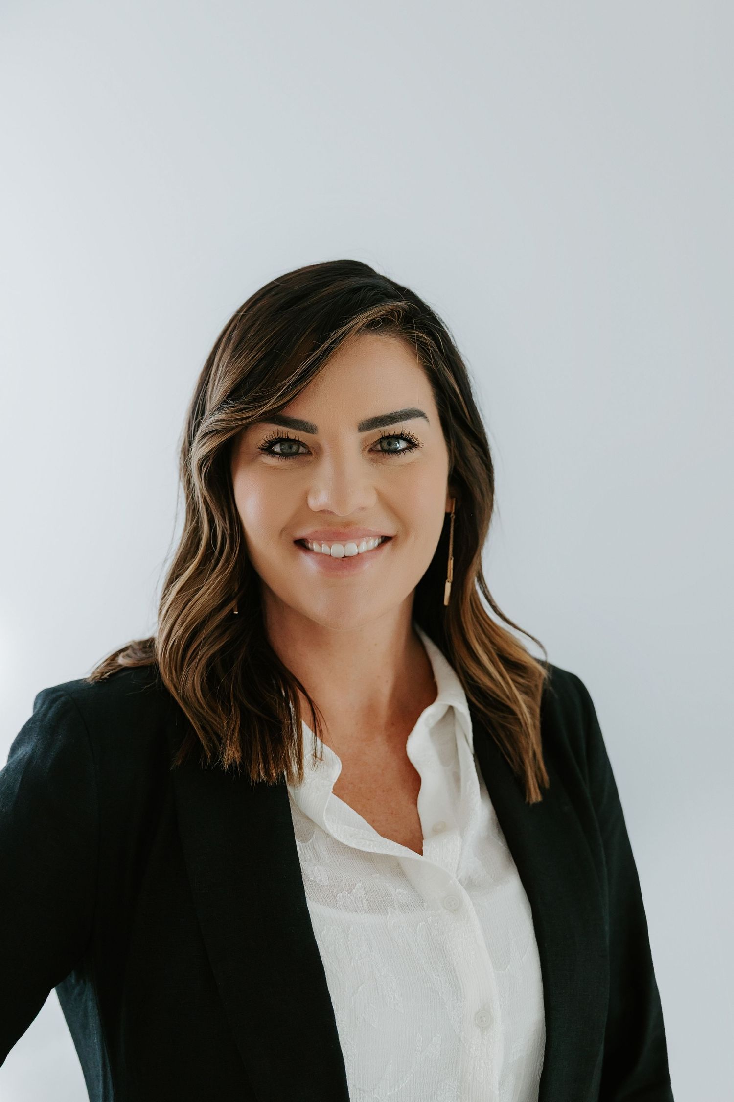 Business portrait series in black blazer and white shirt against light backdrop.