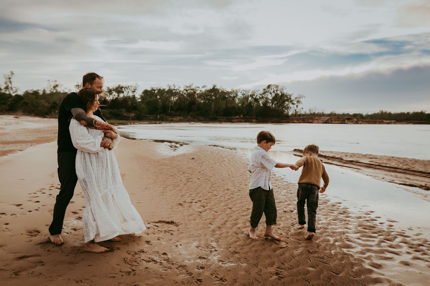 Family walking and playing together on sandy beach at sunset.