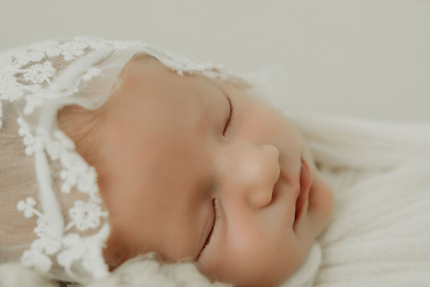 Serene portrait of sleeping baby in soft natural light against neutral background.