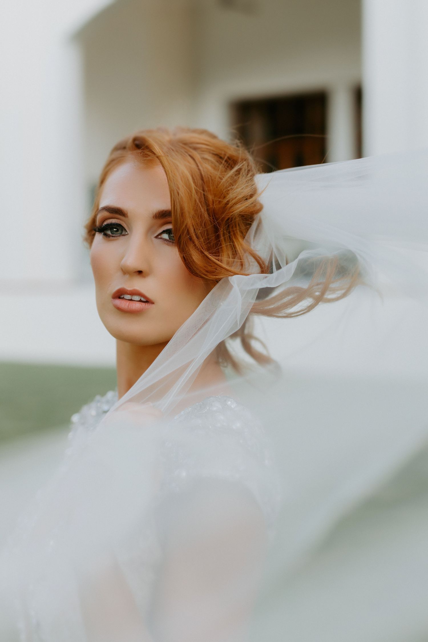 Ethereal bridal portrait with flowing veil catching wind against soft background.