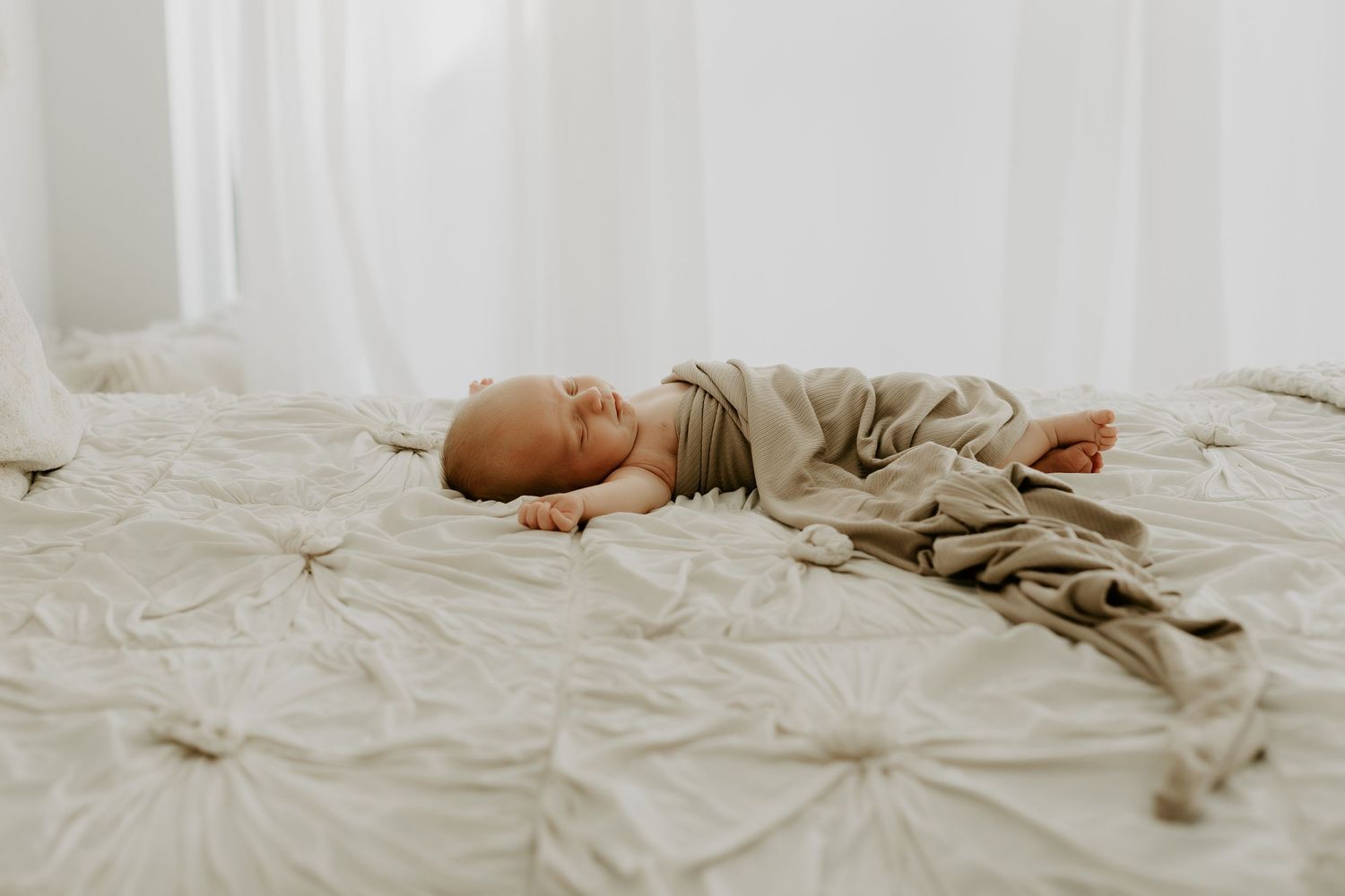 Two siblings share a tender moment while lying together on white bedding.