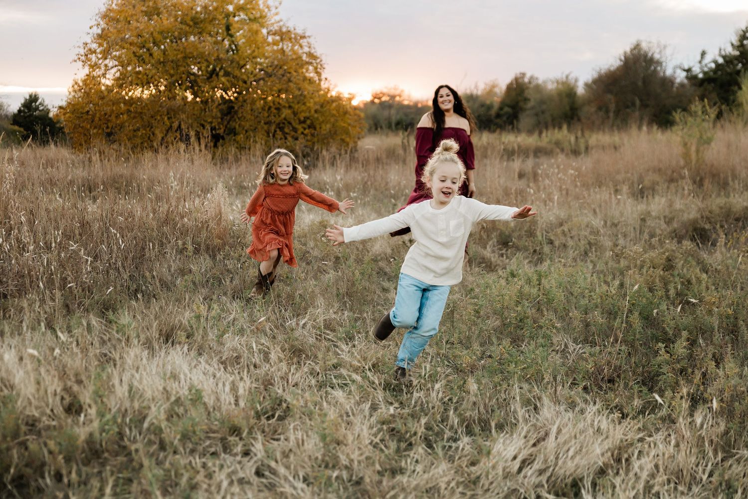 People playing and posing in a field of tall autumn grass at sunset.