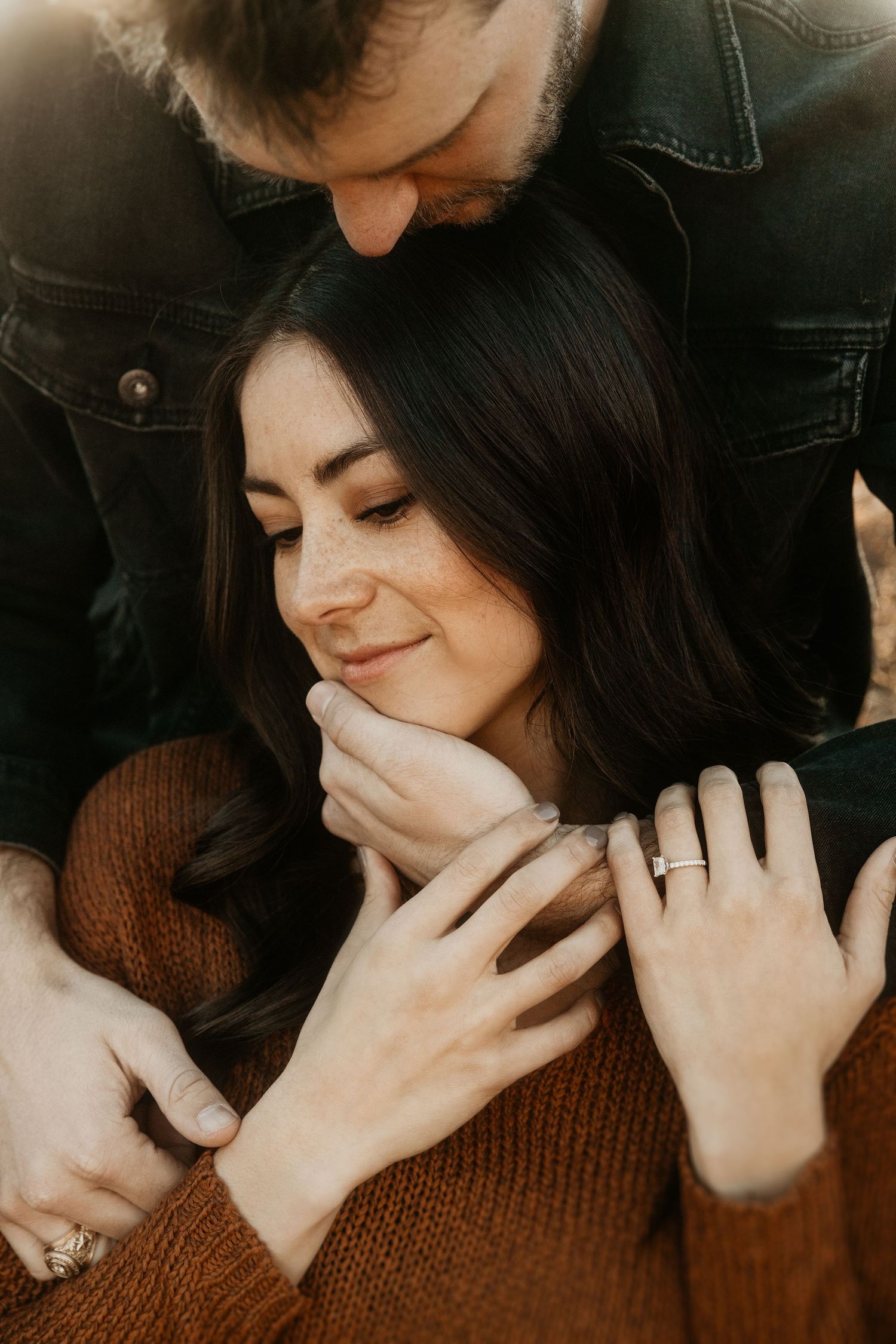 Intimate close-up of couple embracing in warm autumn lighting.