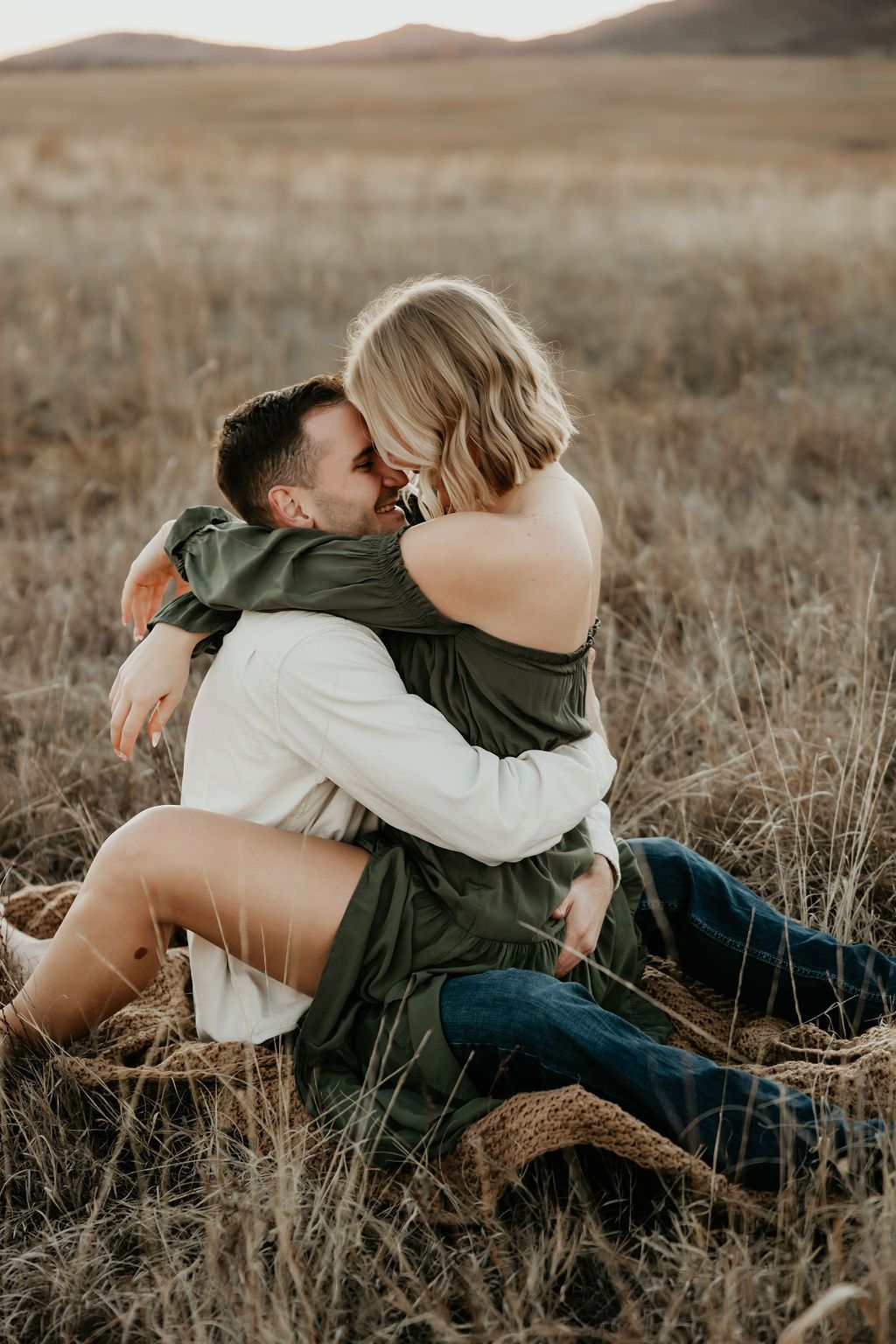 Couple lying together affectionately in a dry grass field.