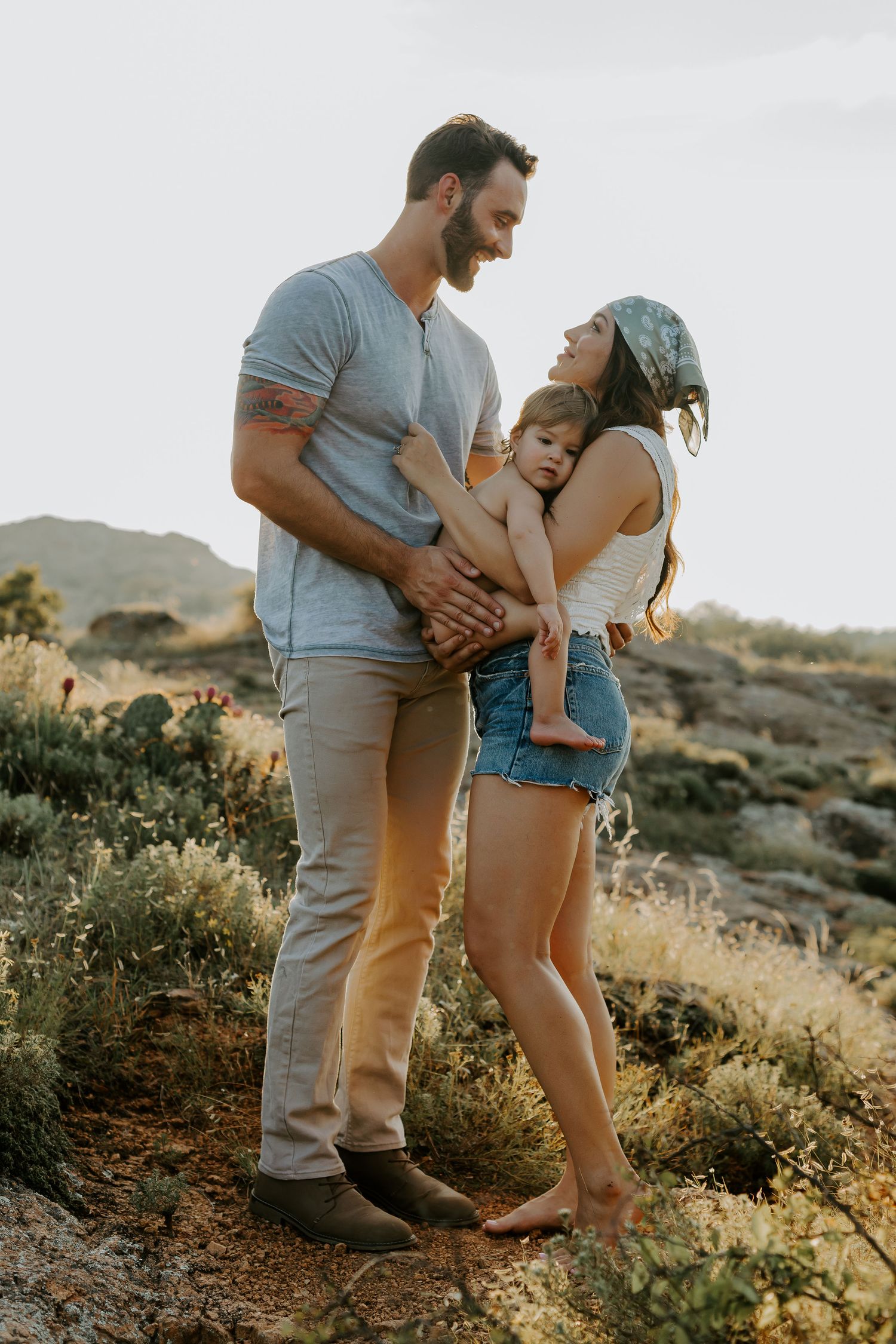 An outdoor family photoshoot on rocky terrain during golden hour.