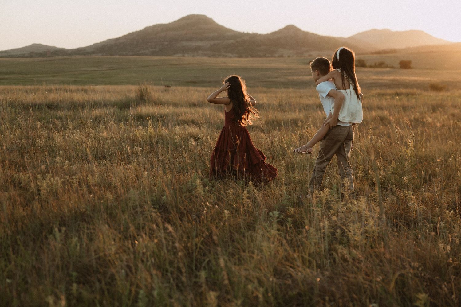 People walking through a sun-drenched field with mountains on the horizon.