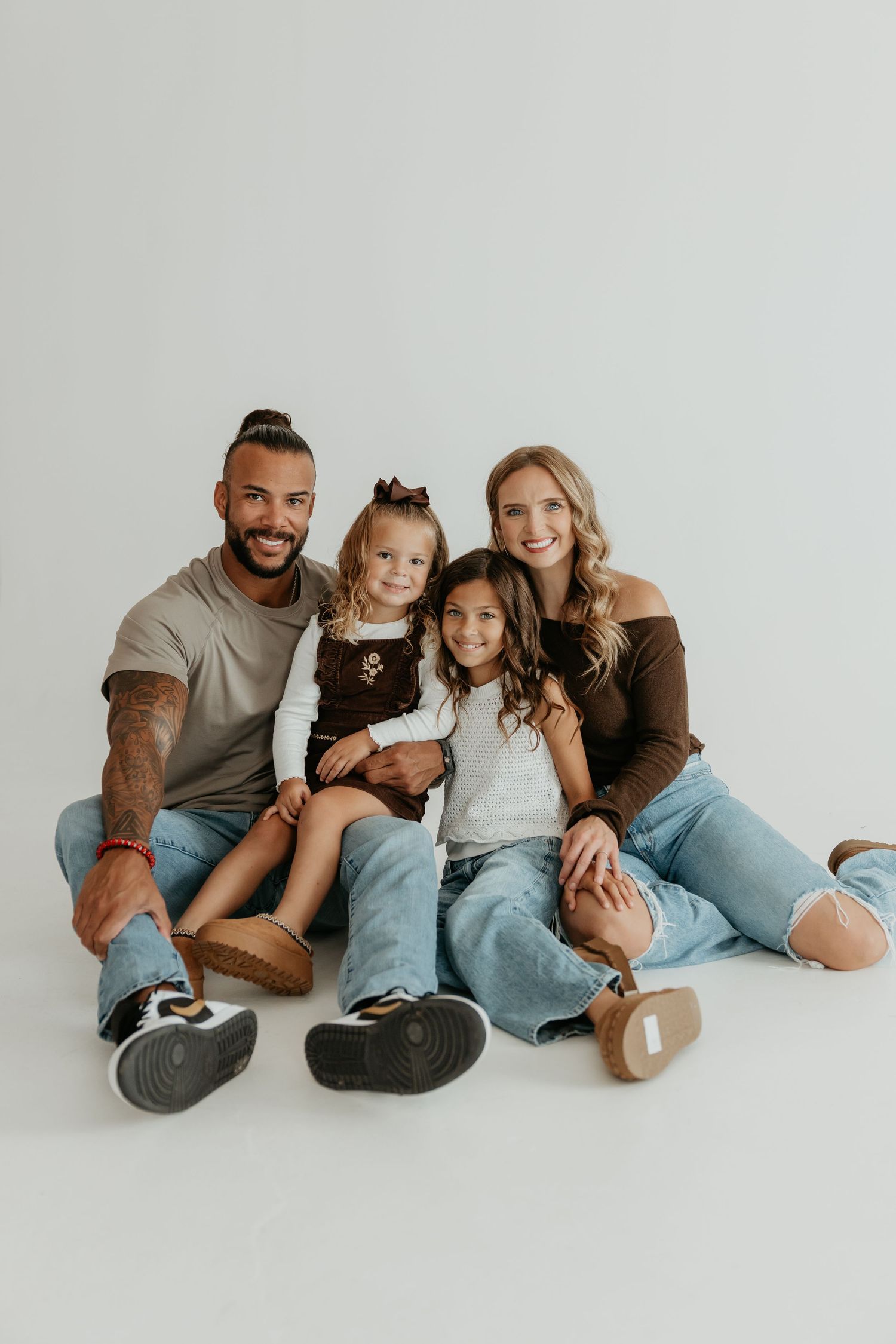 Modern family portrait against white background in casual denim outfits.