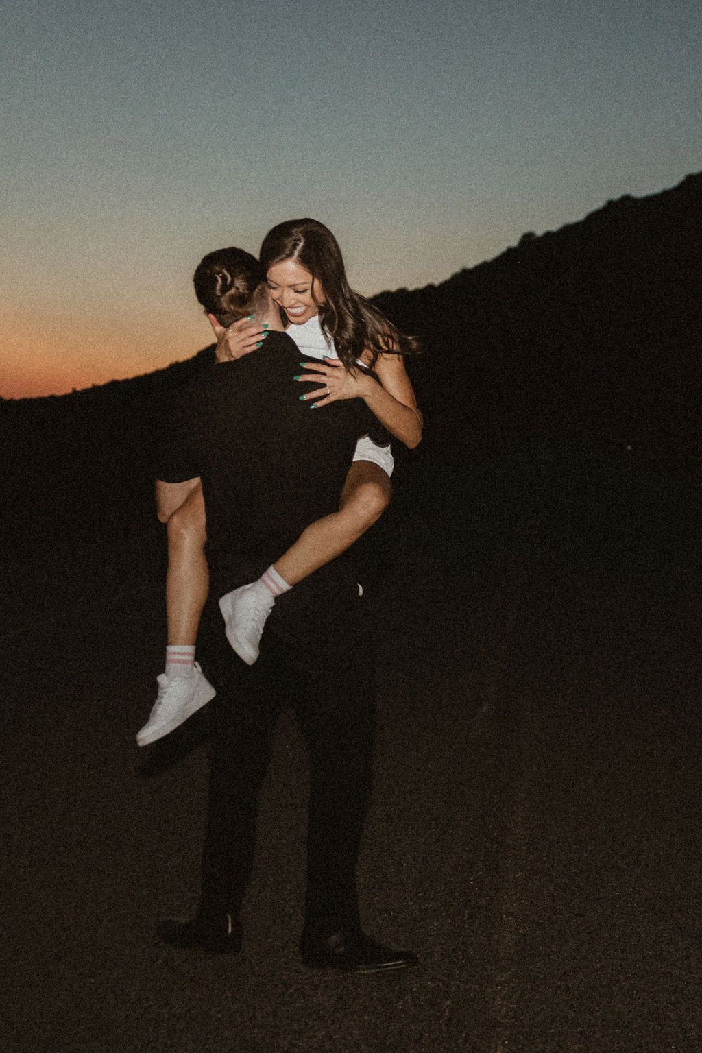 Silhouetted figures dancing at sunset, creating romantic poses against darkening sky.