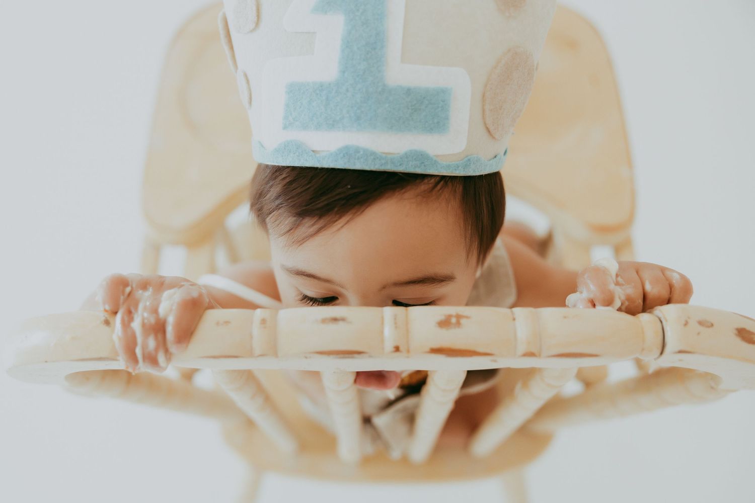 A wooden high chair decorated for a birthday celebration against a white background.
