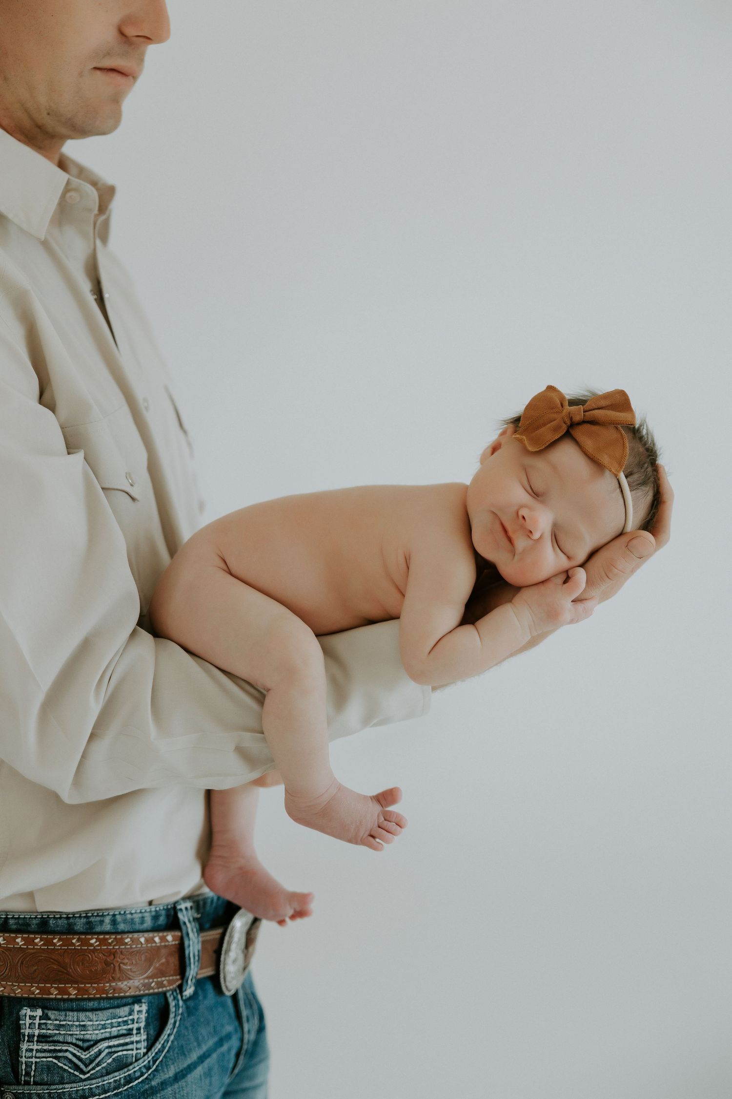 Baby sleeping peacefully while being held against white shirt.