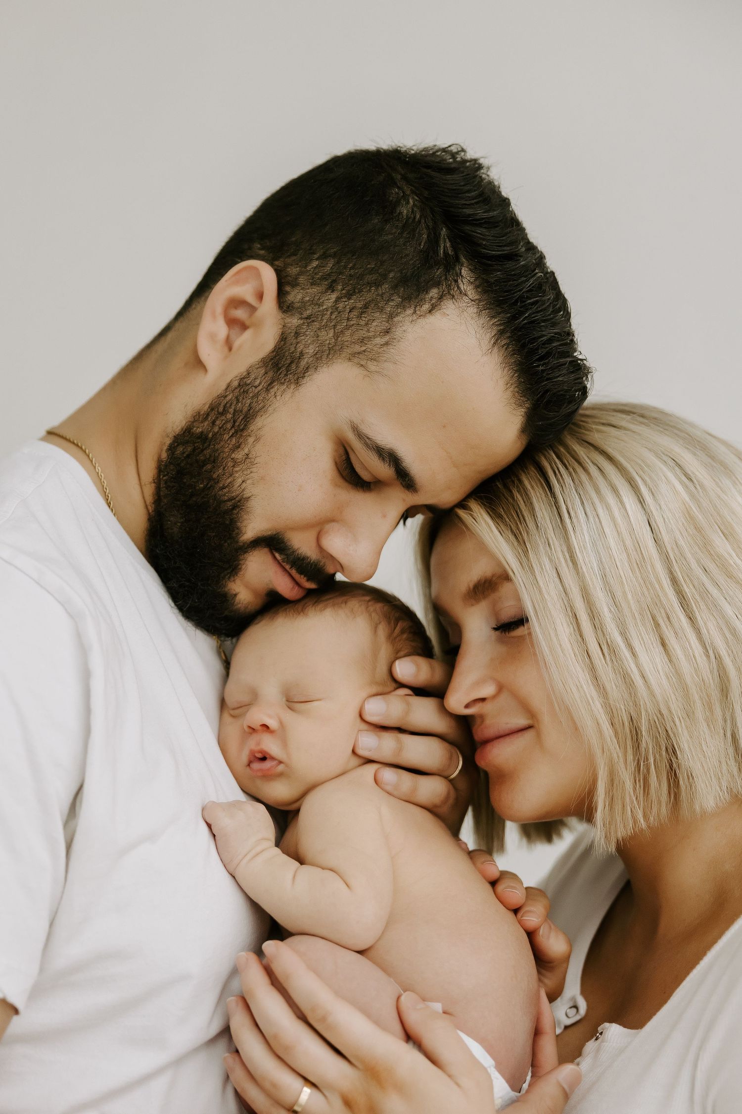 Intimate family portrait with tender embraces against white background.