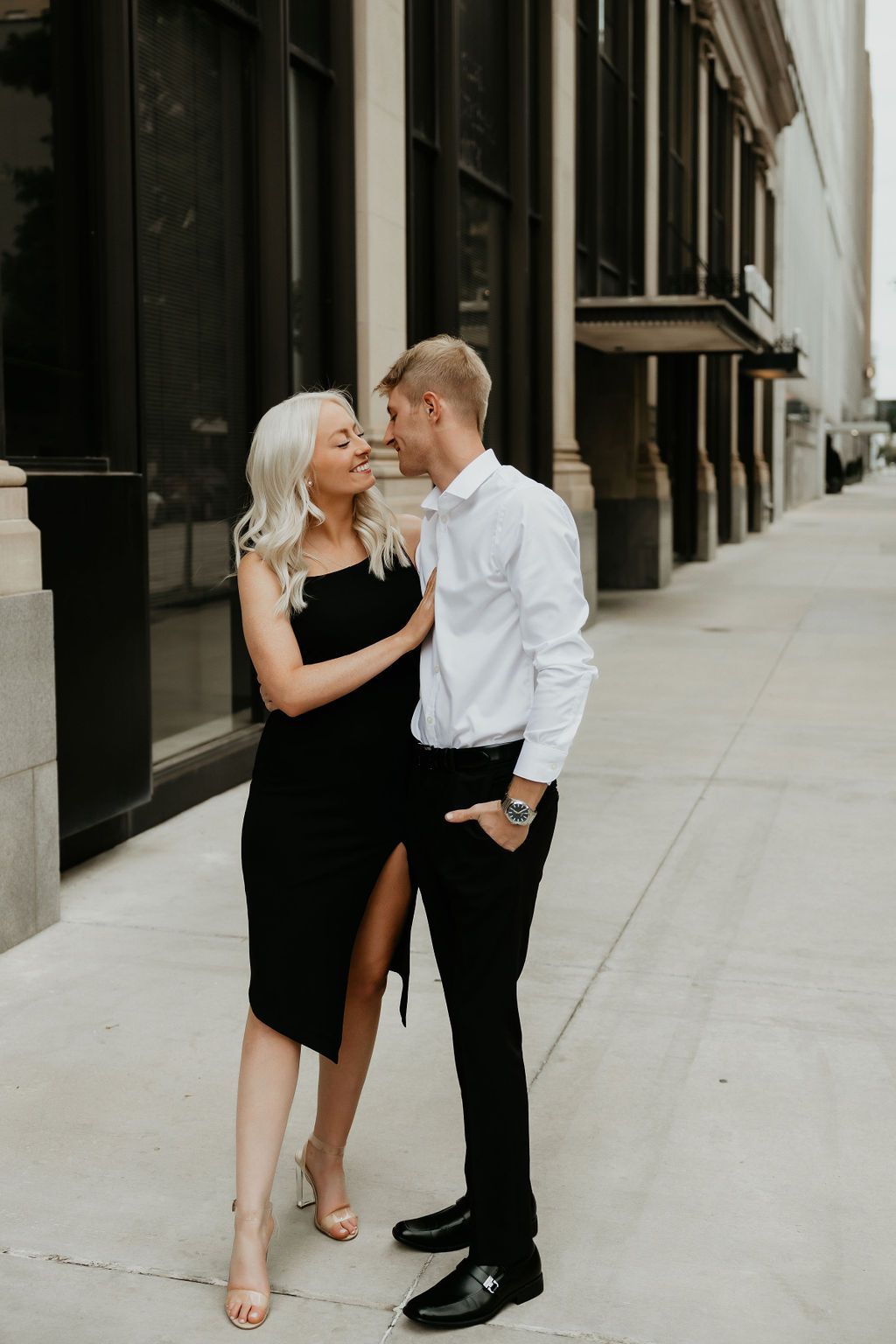 Stylish couple poses together against modern urban architecture.