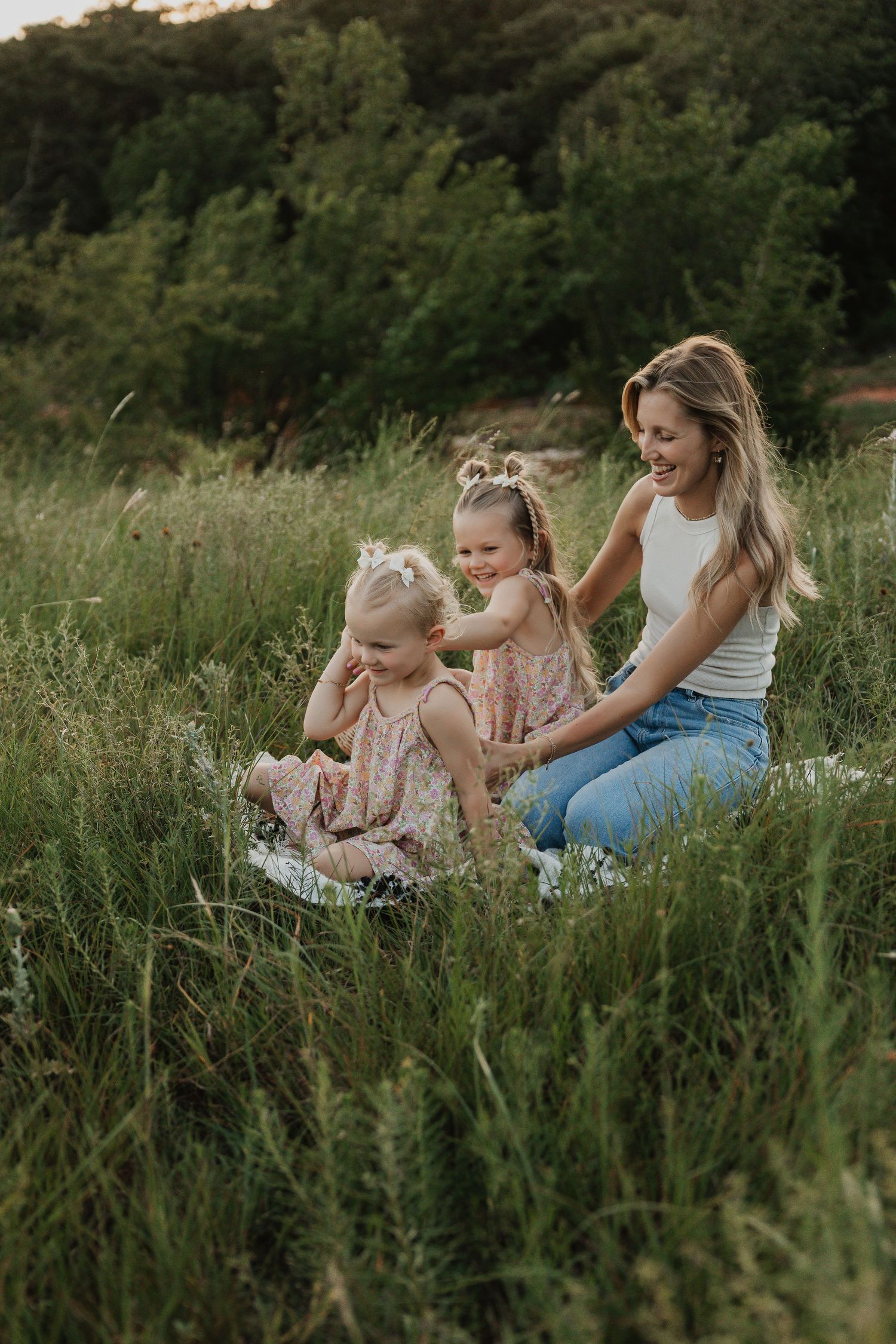 A joyful outdoor family photoshoot in tall grass during golden hour.