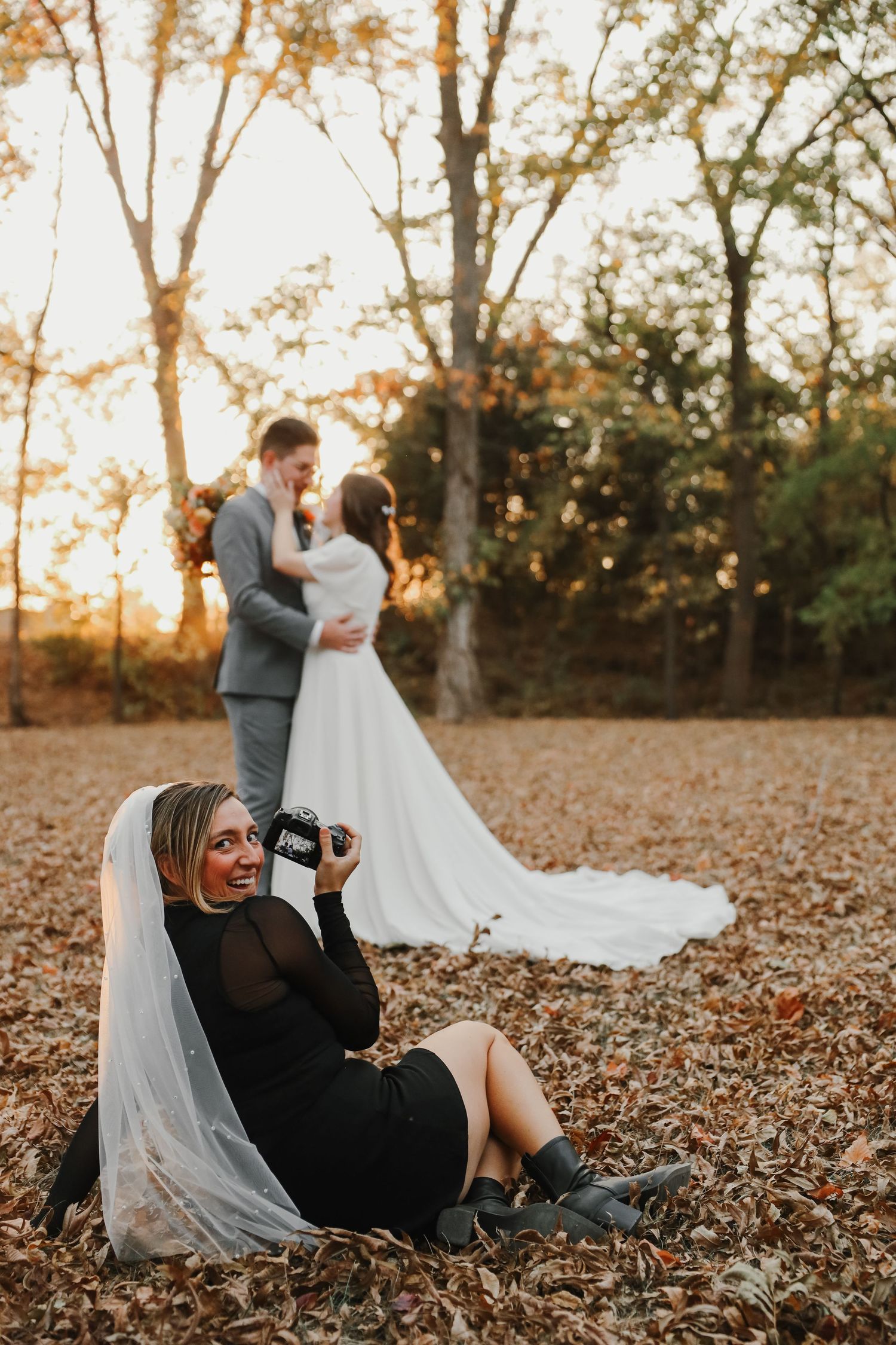 A couple poses together during an autumn sunset photoshoot with fallen leaves in a wooded area.