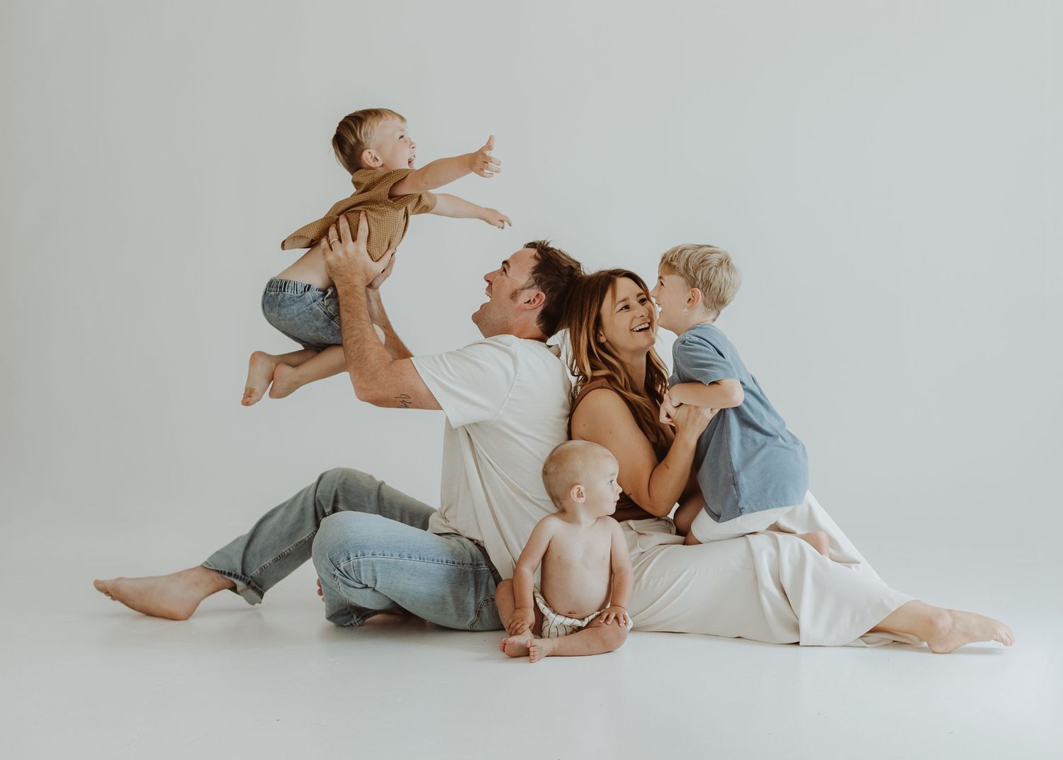 Playful family moments captured against minimalist white backdrop.