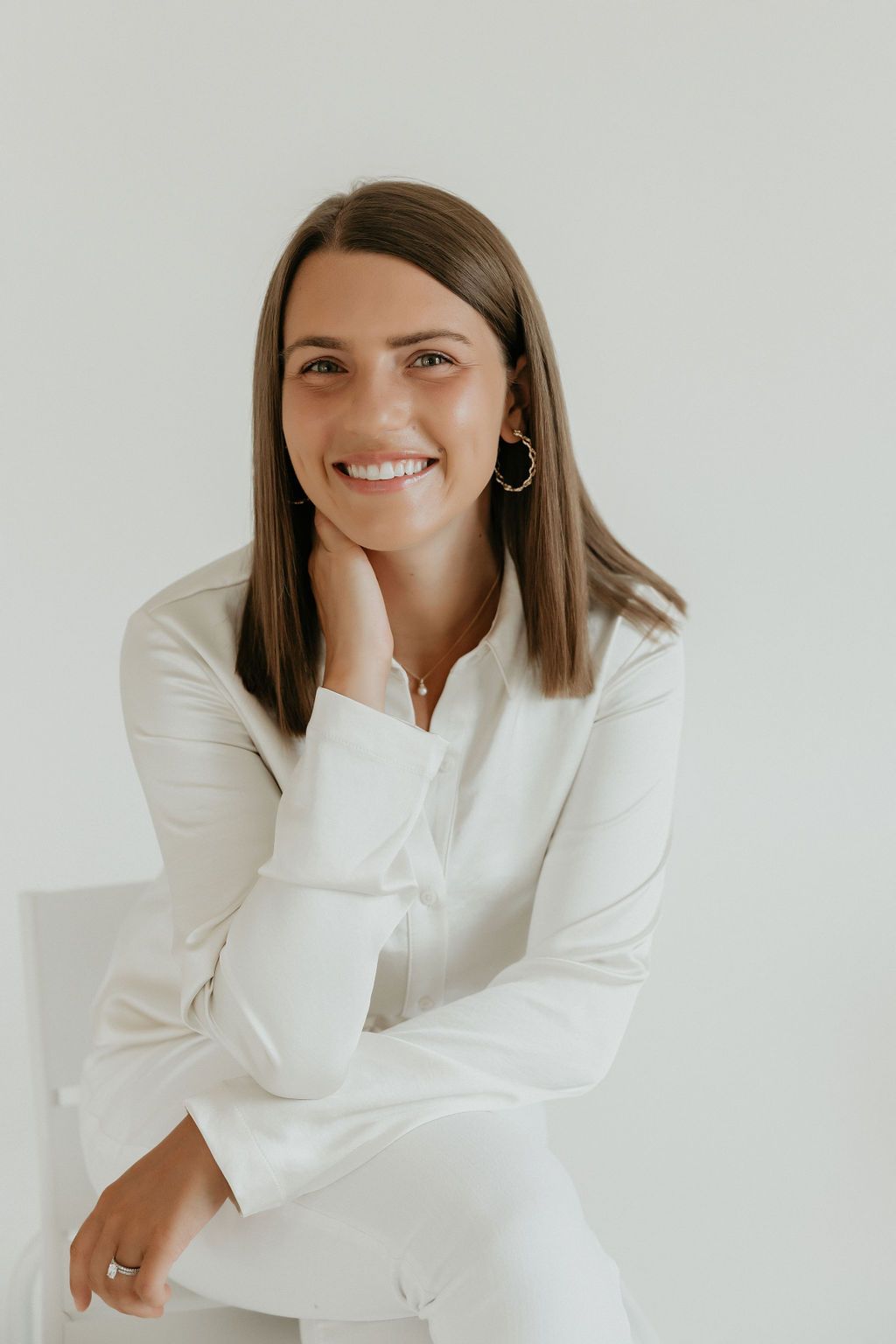 Creative professional in white blazer poses during studio photoshoot.
