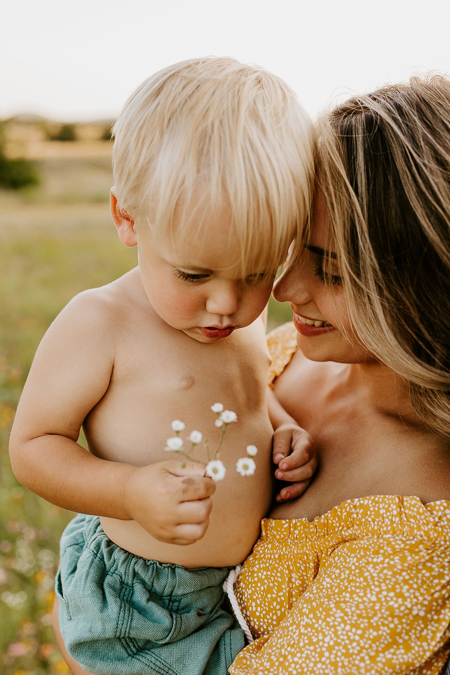 Tender moment shared between parent and child in sunny outdoor setting.