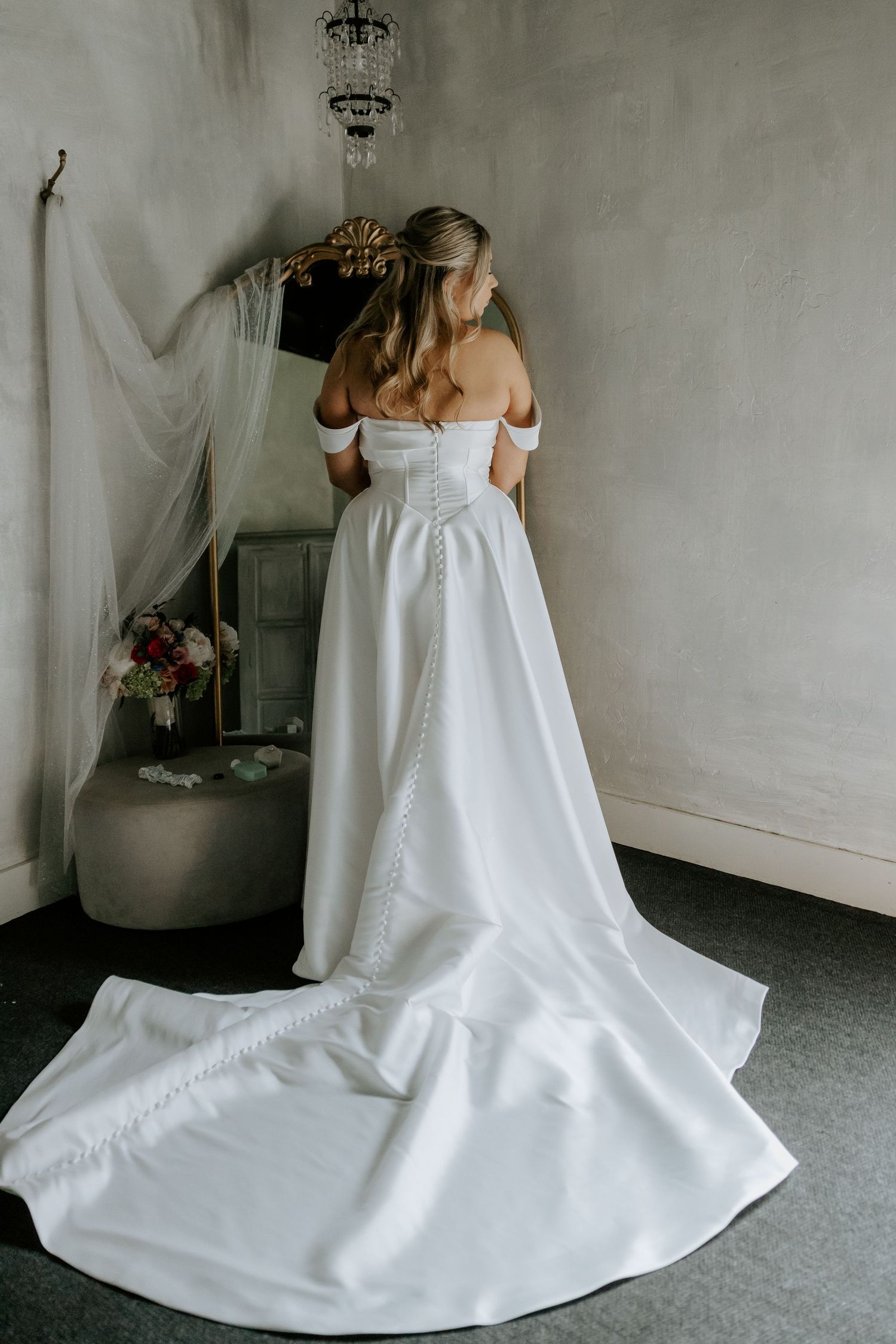 Wedding dress with dramatic train spread across grey floor in multiple artistic angles.