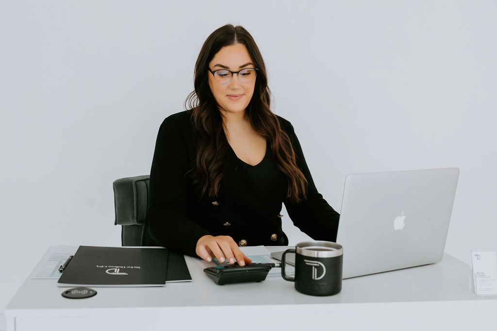 Professional working at desk with laptop and camera equipment.