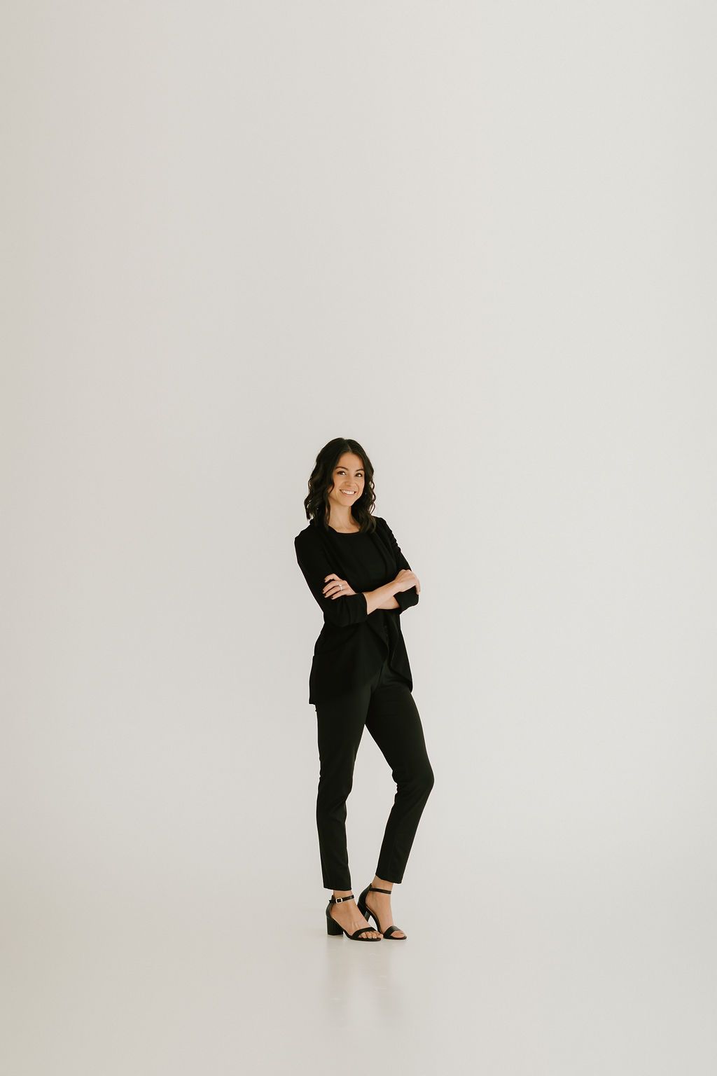 Professional portrait of someone in all black business attire against white background.