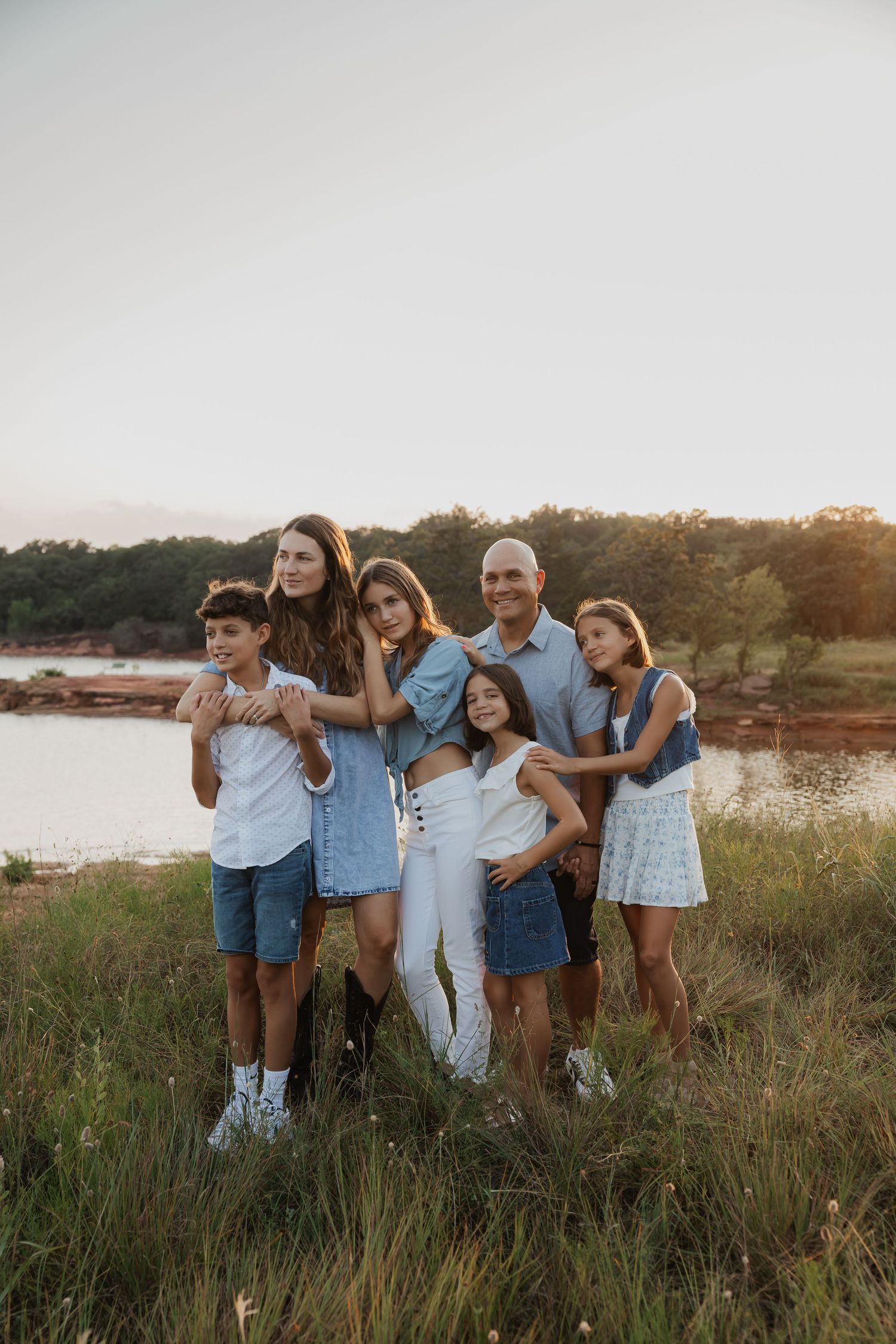 Large group photo of friends or family members posing together outdoors at sunset.