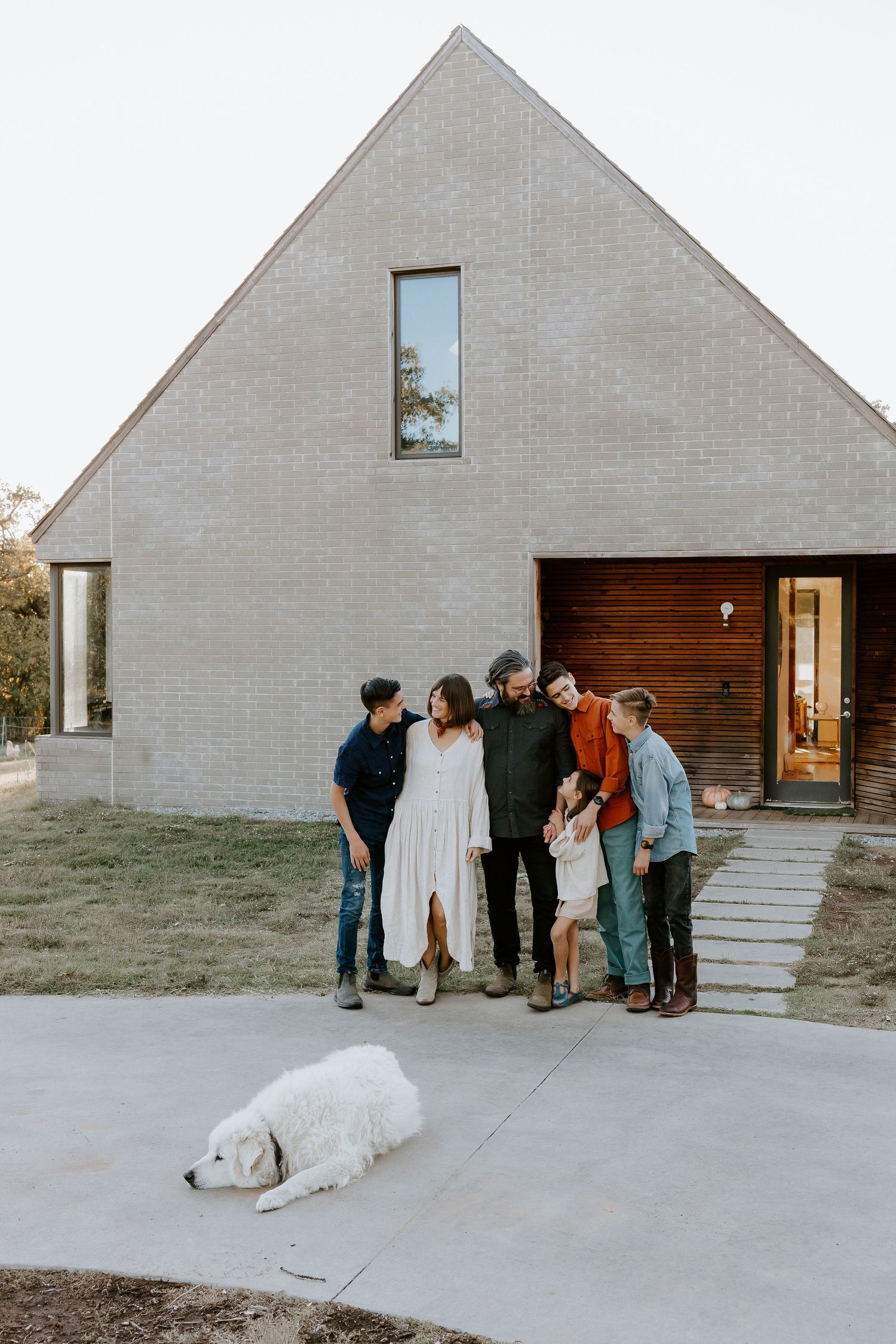 A modern minimalist house exterior with white walls and people gathered outside.