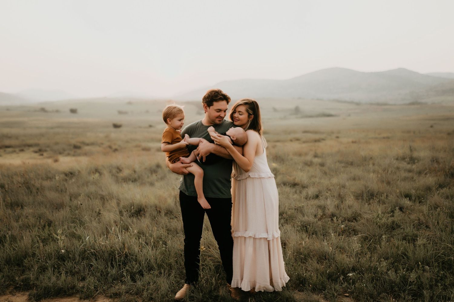 Family walking together through a vast prairie landscape at sunset.