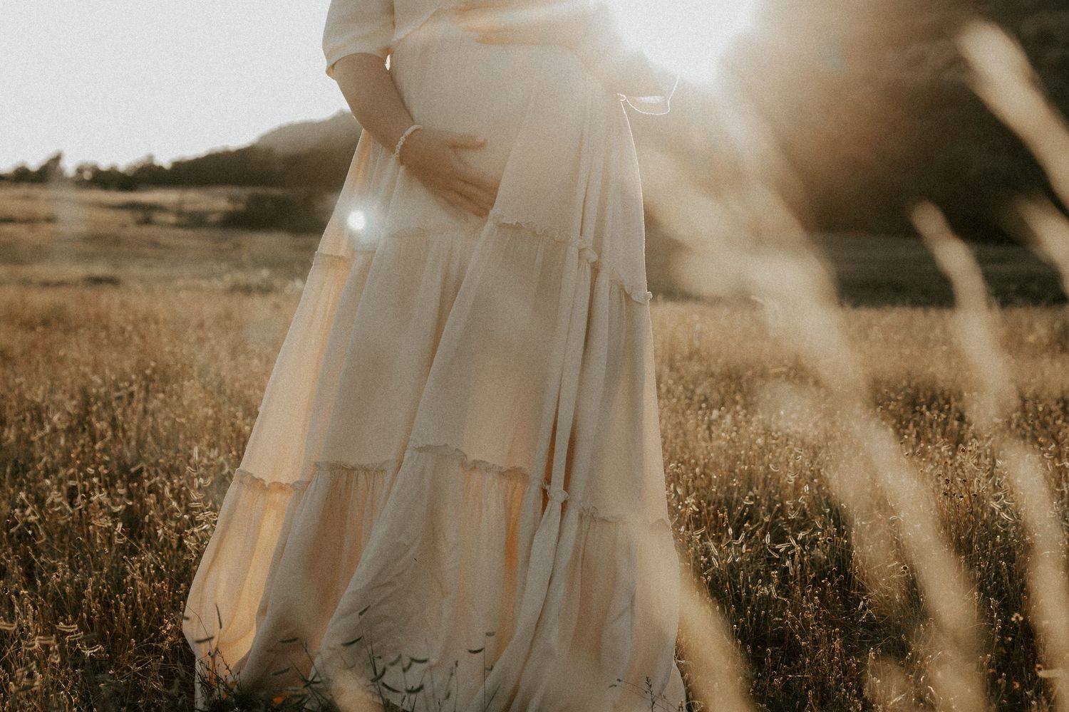 Ethereal maternity portrait in flowing dress captured during golden hour.