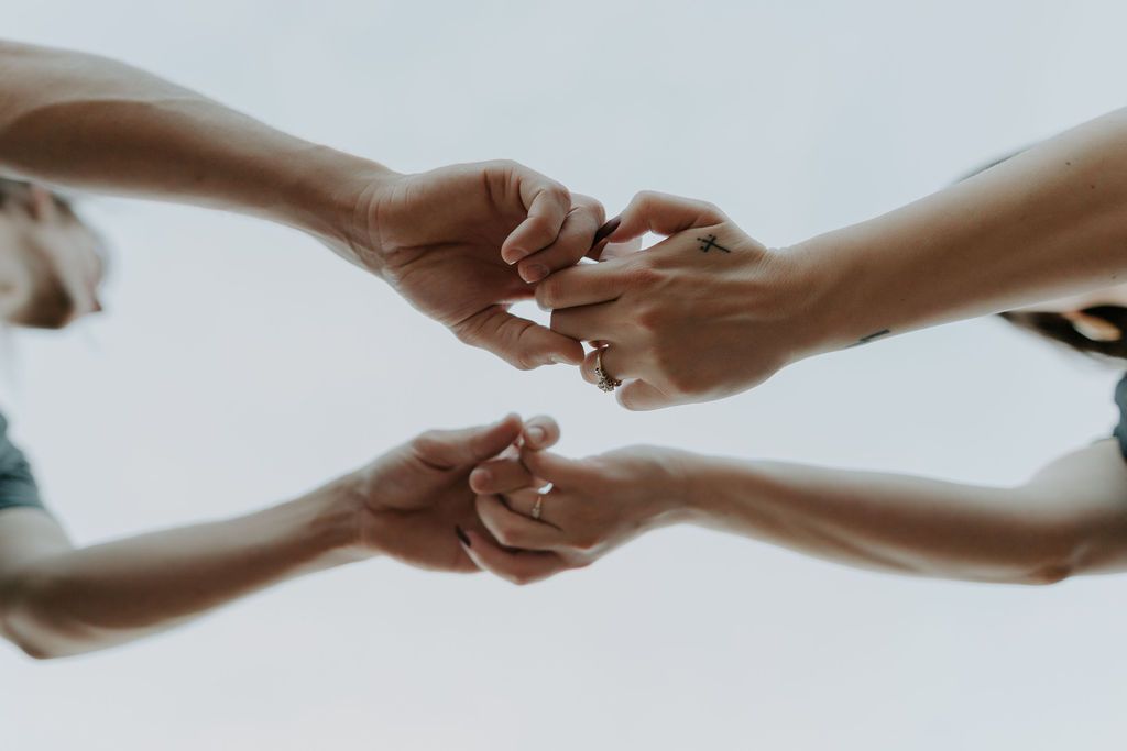 Series of hands reaching and holding each other against white background.