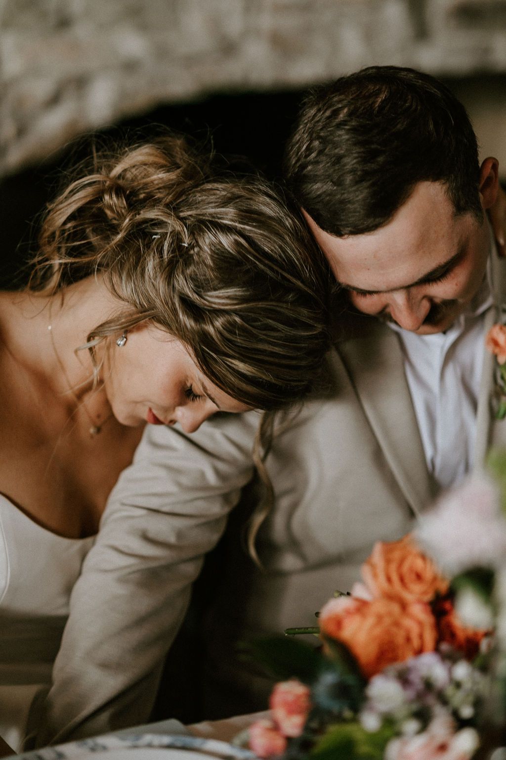 A candid moment shows a couple laughing together with orange roses on the table.