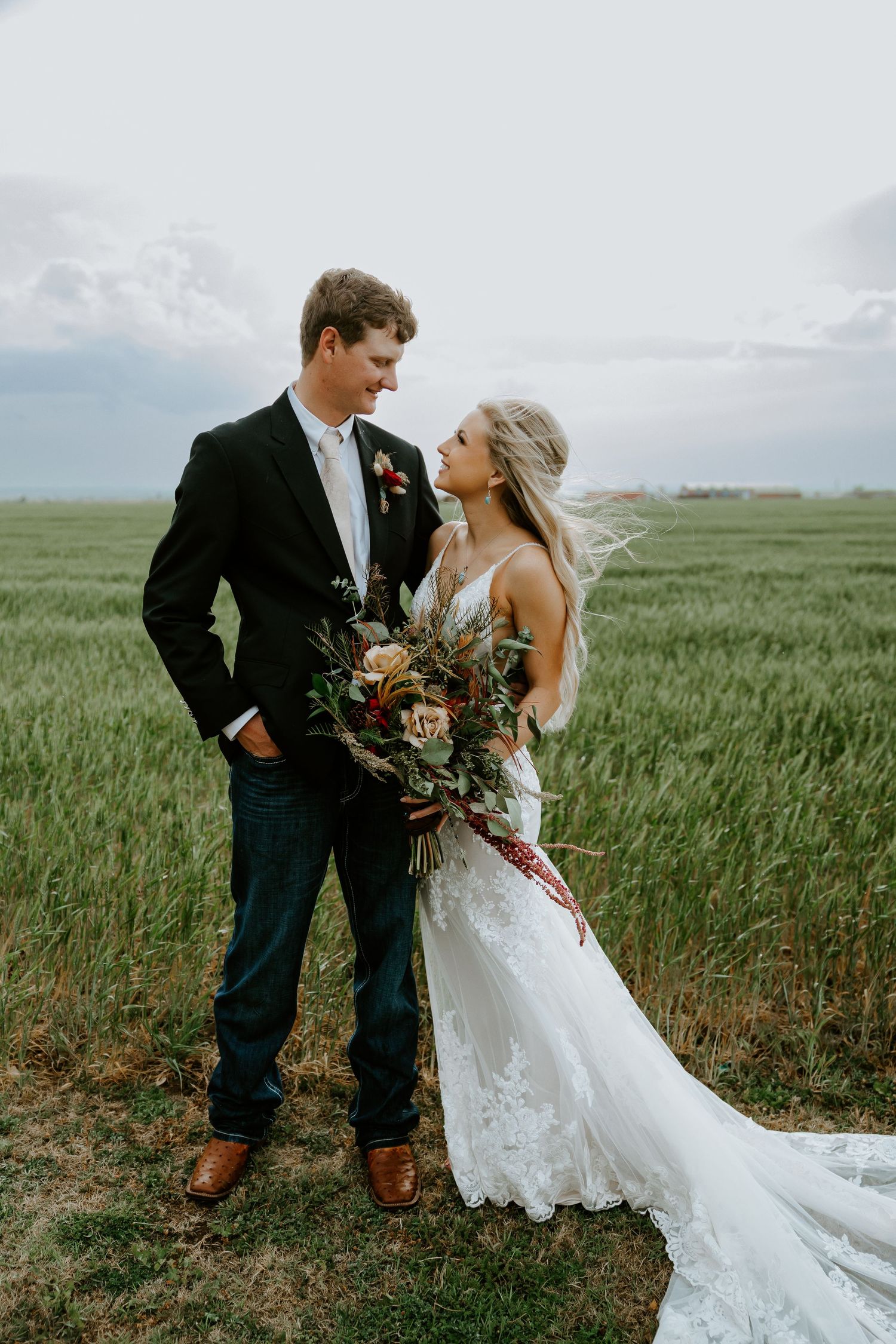 Romantic wedding portraits in a lush green field with moody sky backdrop.