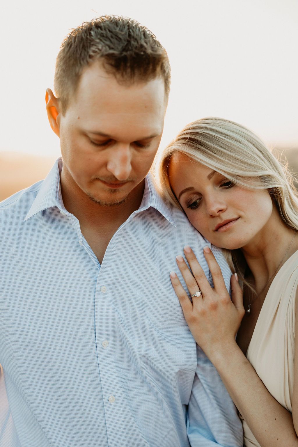 Tender couple in light colored clothing sharing close moments during sunset photoshoot.