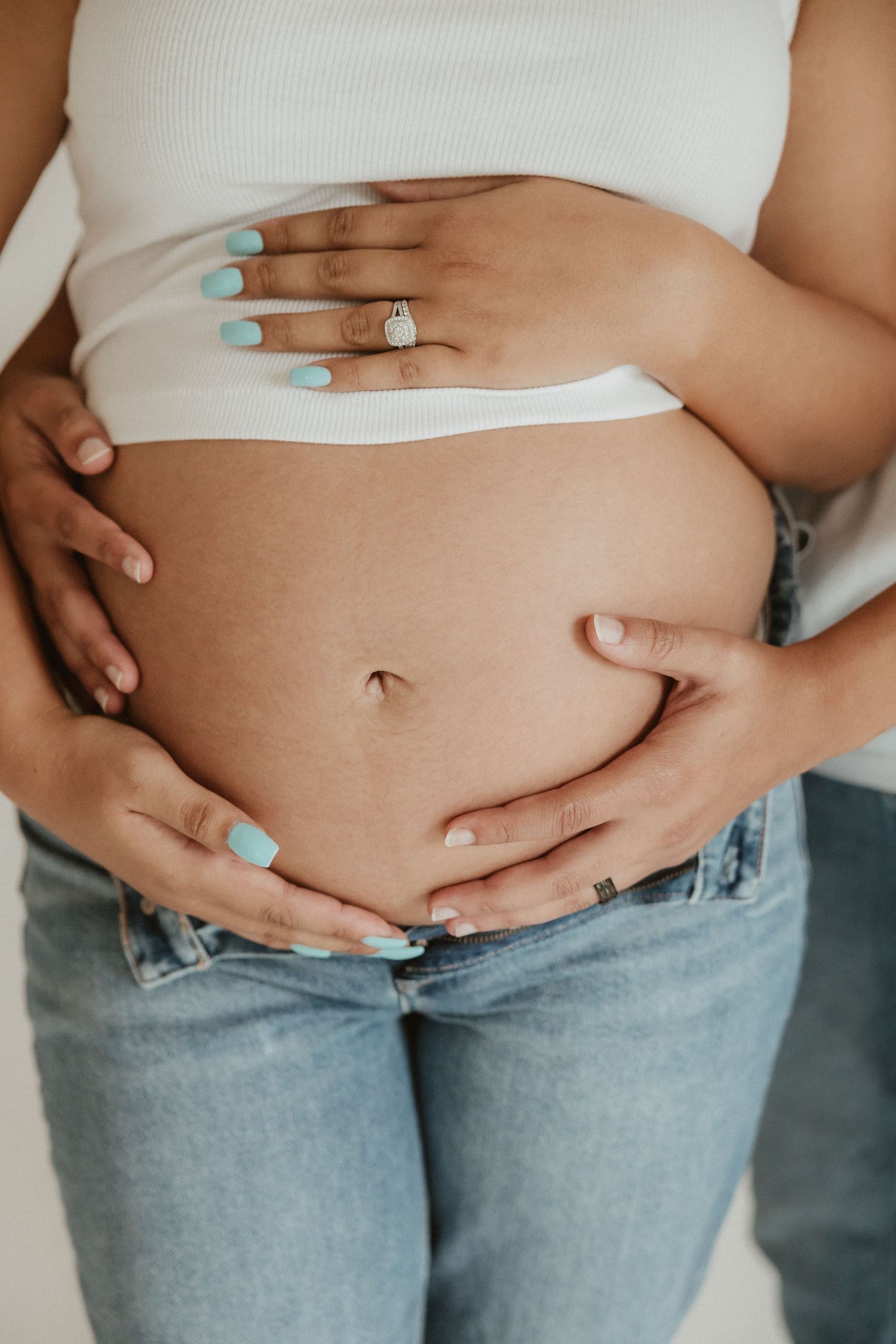 Close-up progression photos of a pregnant belly in jeans showing growth over time.