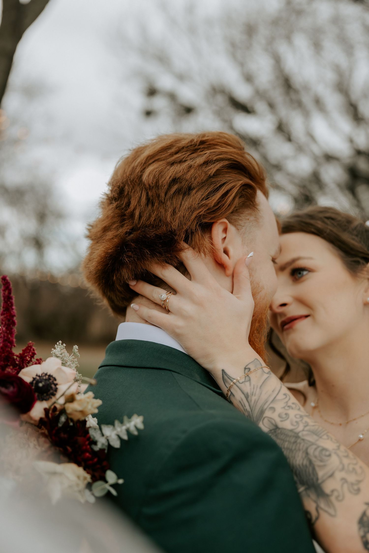 Close-up romantic moment with burgundy floral accents in winter setting.