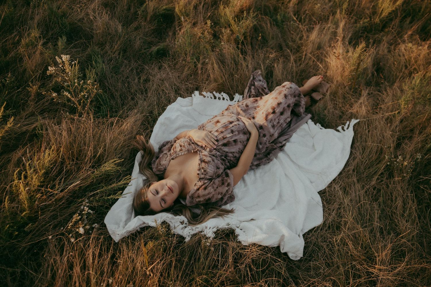 Artistic outdoor photography in field with flowing white fabric at golden hour.