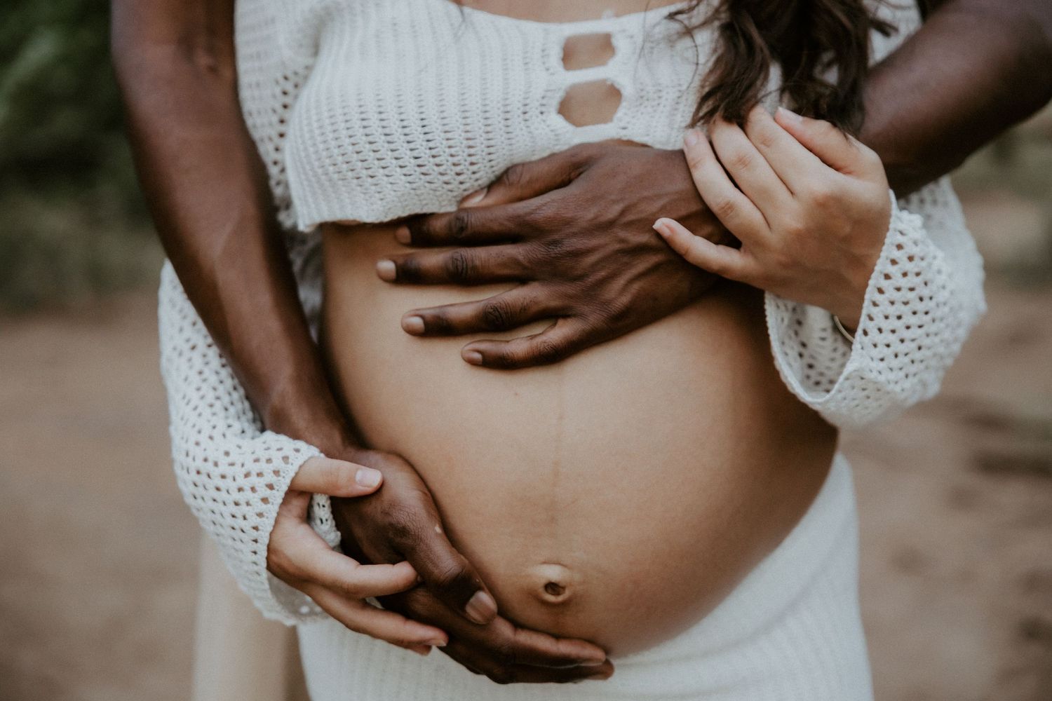 Series of intimate black and white photos showing hands cradling a pregnant belly.