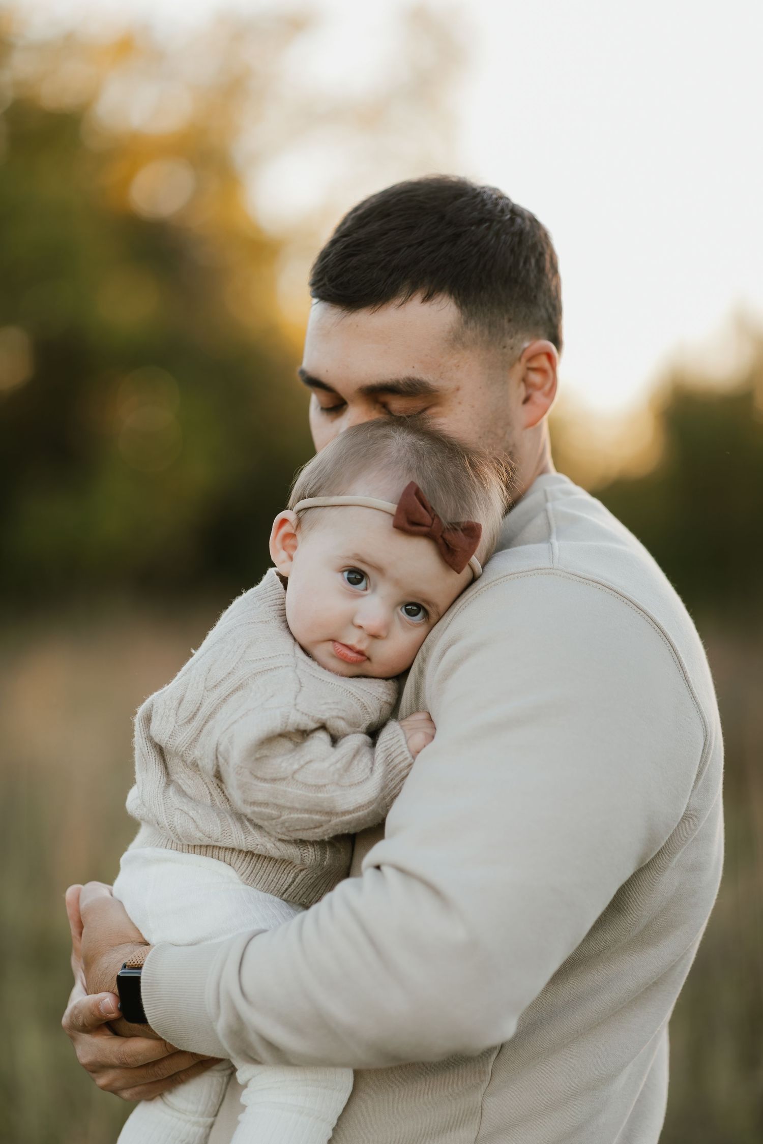 Tender moments between parent and child wearing neutral colored sweaters in soft lighting.