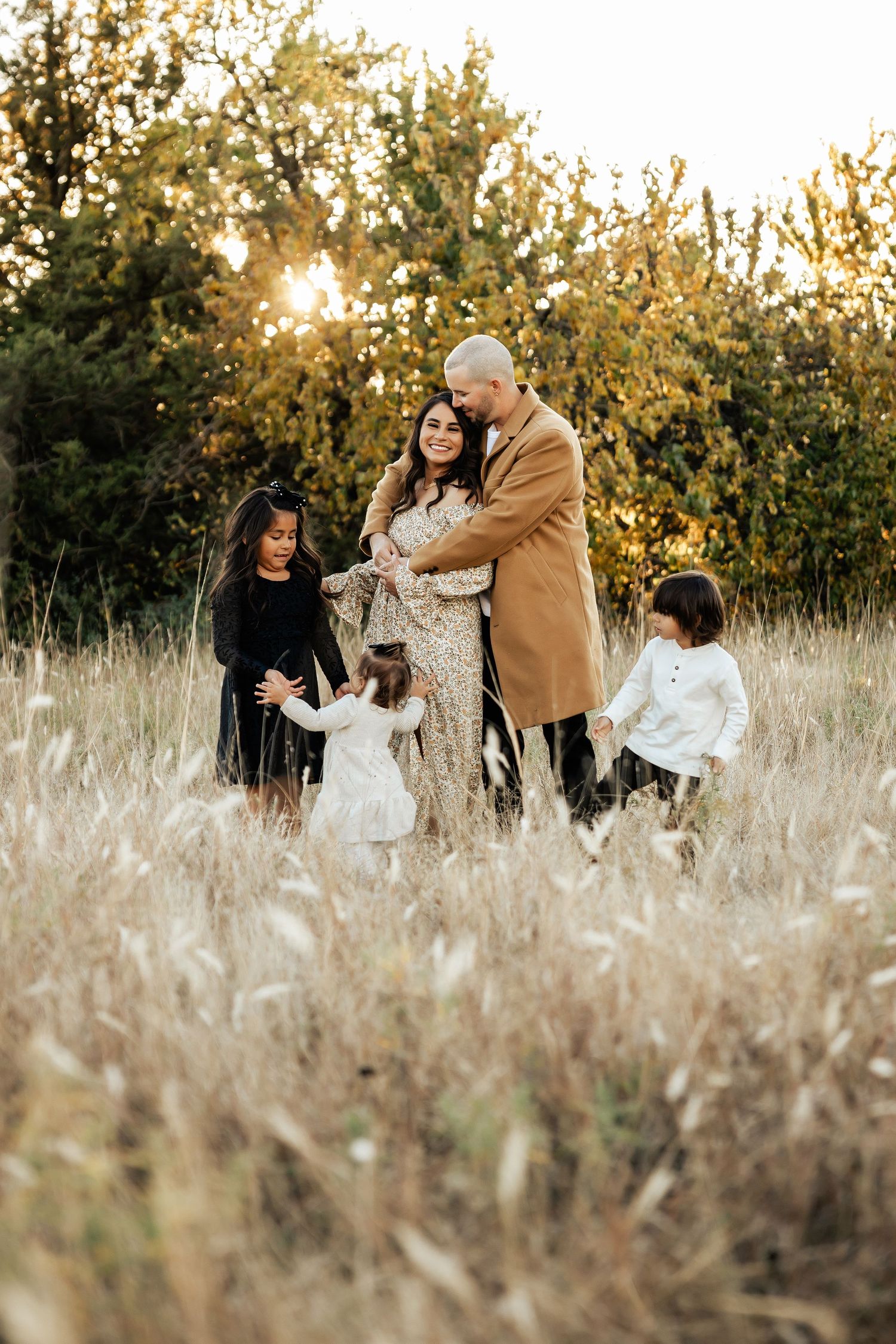 Playful family moments captured in tall grass during golden hour.